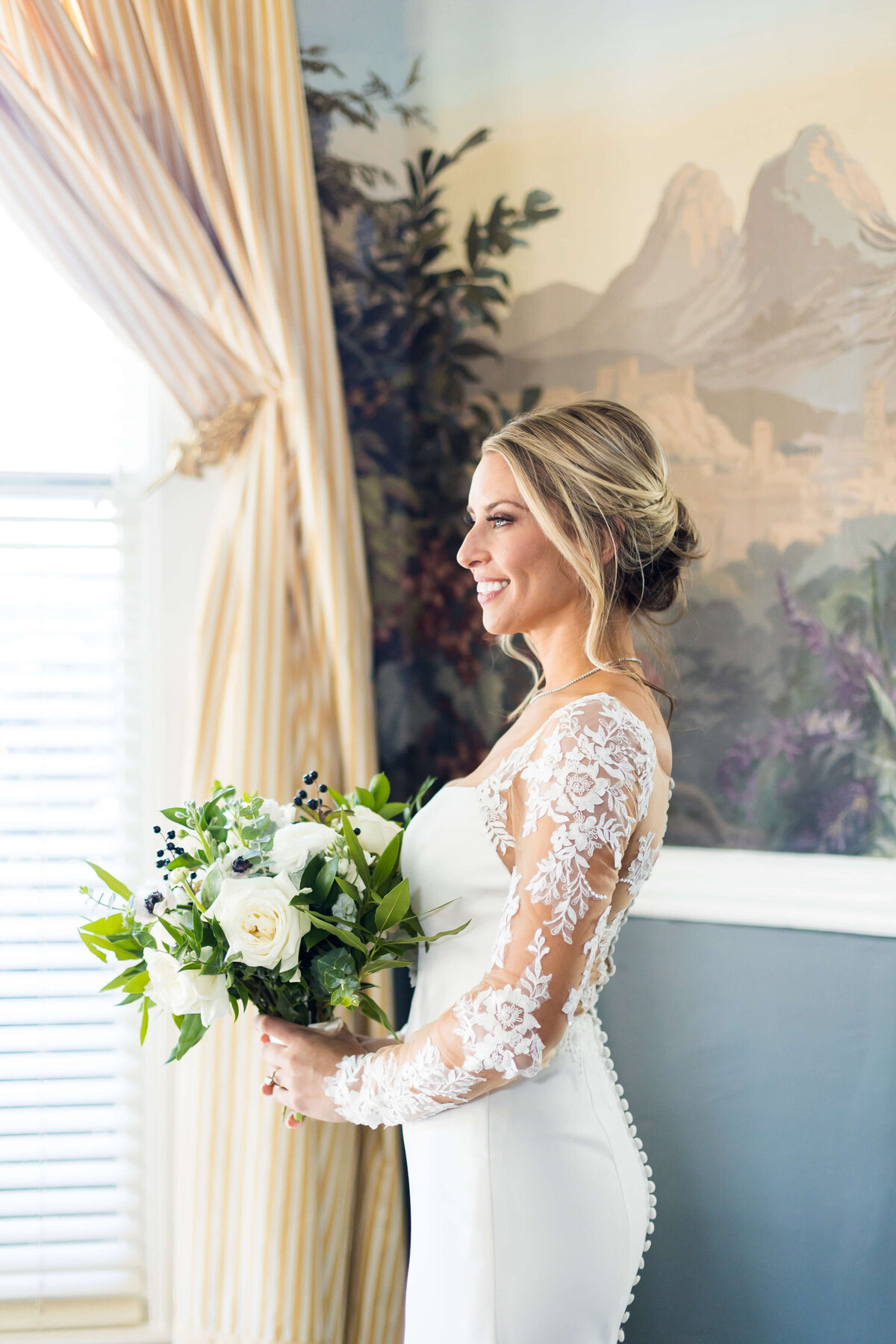Bride looking out the window at The Carrick House holding bouquet of florals by Blooms and Blossoms