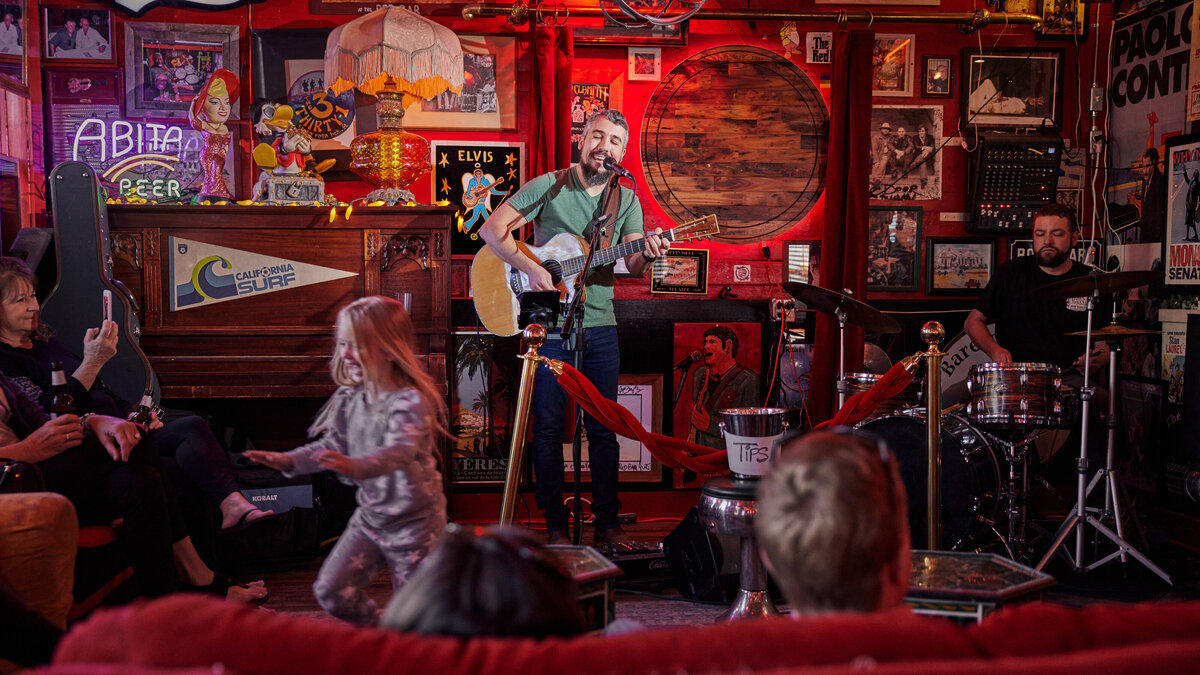 A person playing guitar on stage at a bar