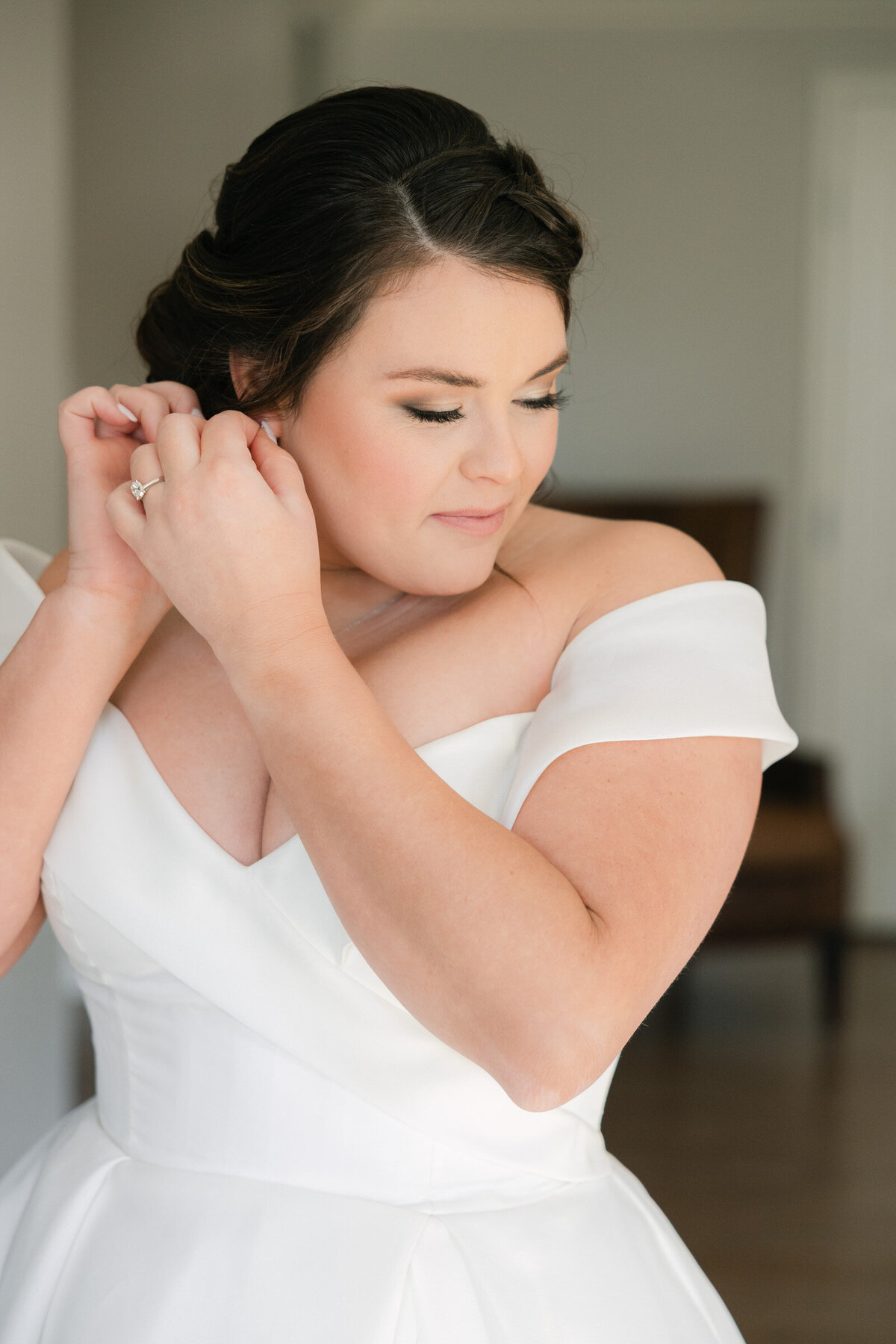 bride putting on earrings at The Adolphus in Dallas, captured in a timeless and elegant portrait highlighting bridal preparation at this luxury wedding venue.