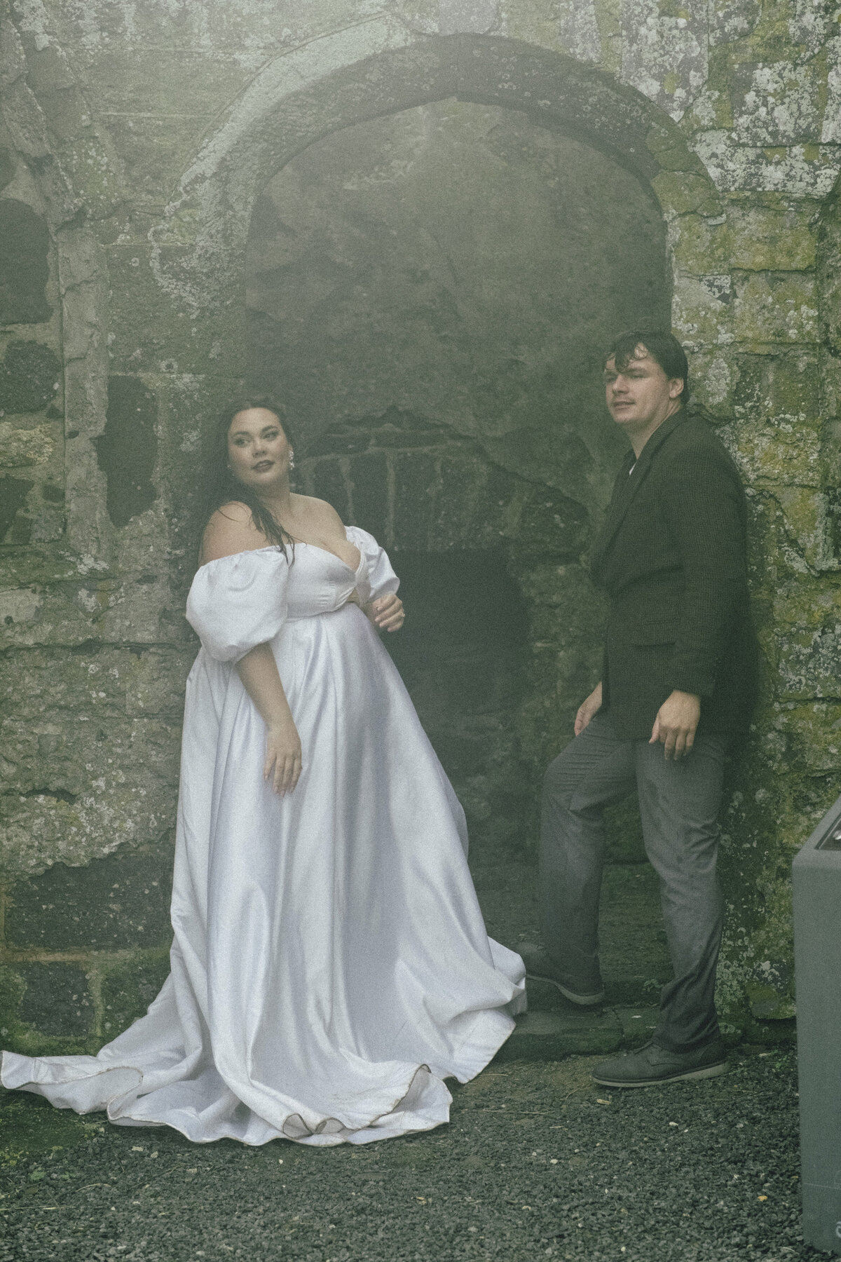 newly married couple leaning against old ruins