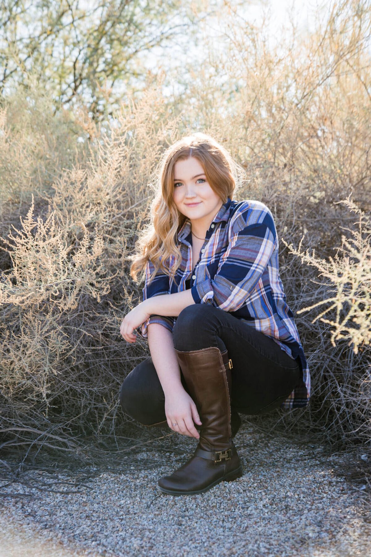 redheaded young woman smiling whilte squatting in the bushes for a picture