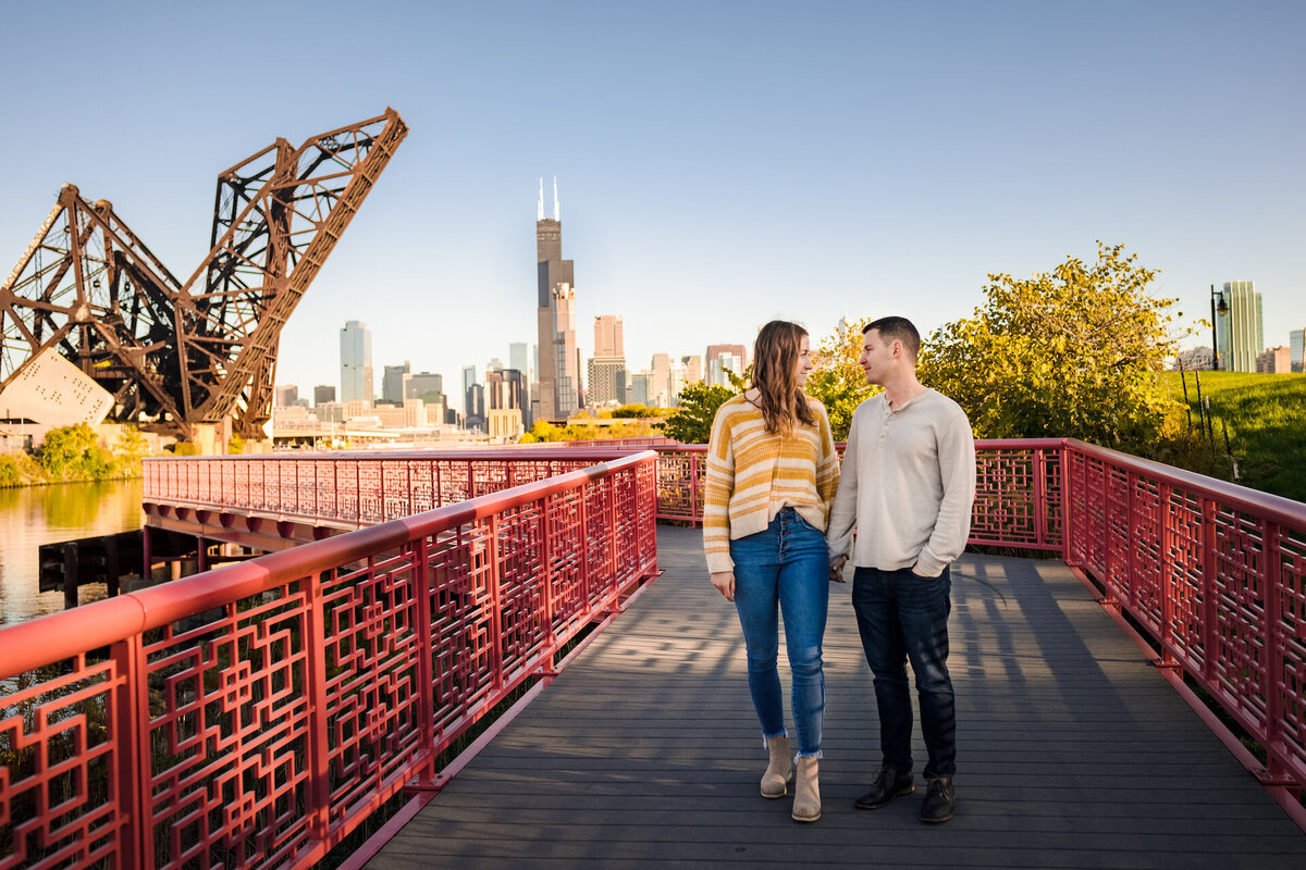 A couple walks down a red bridge  at Pint Tom Memorial Park in Chicago