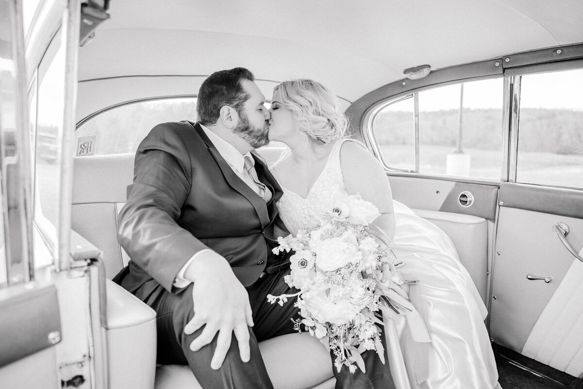 Bride and groom kissing in the back of a classic car