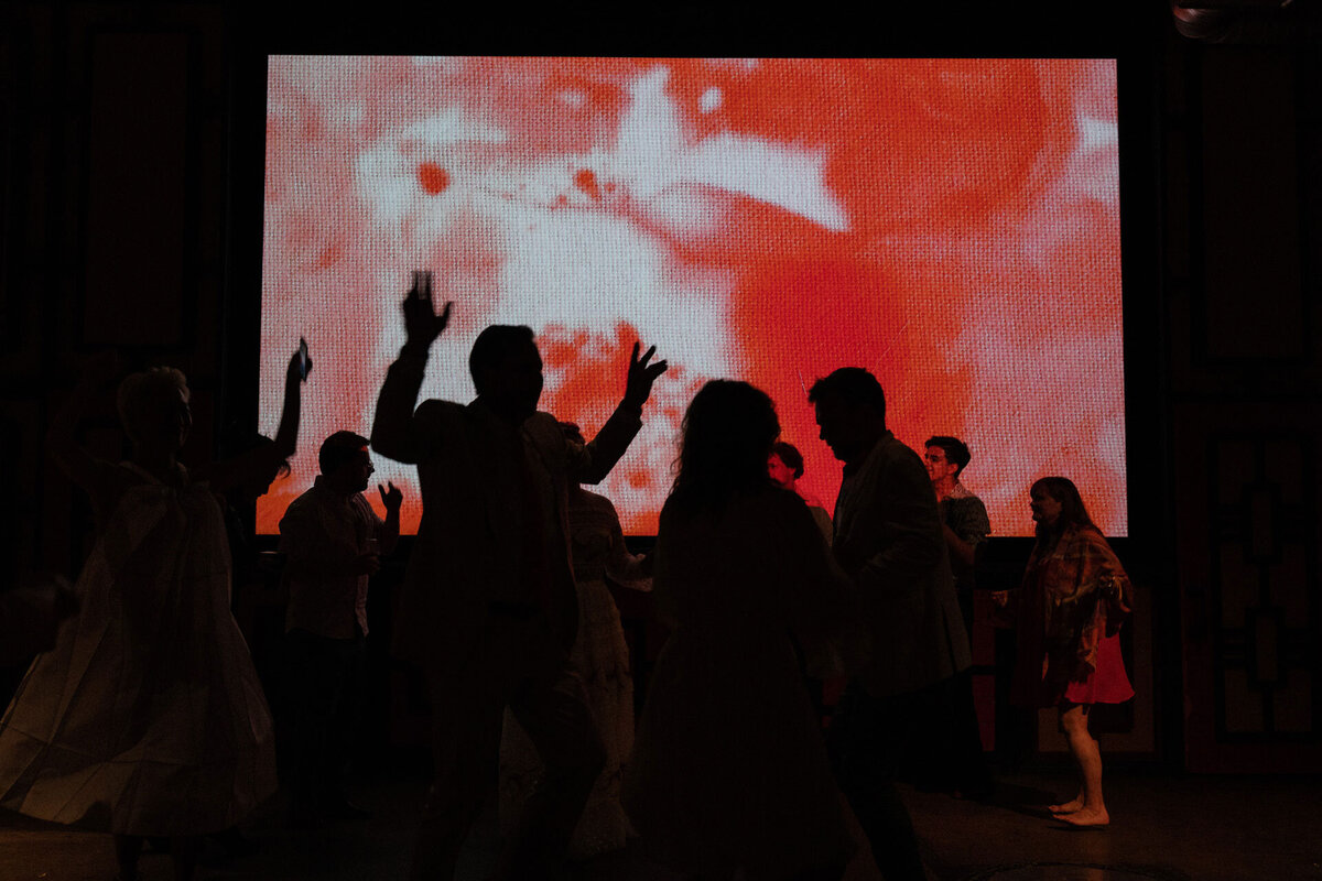 wedding guests dancing at smog shoppe in los angeles with fabric patterns and textures projected on a screen
