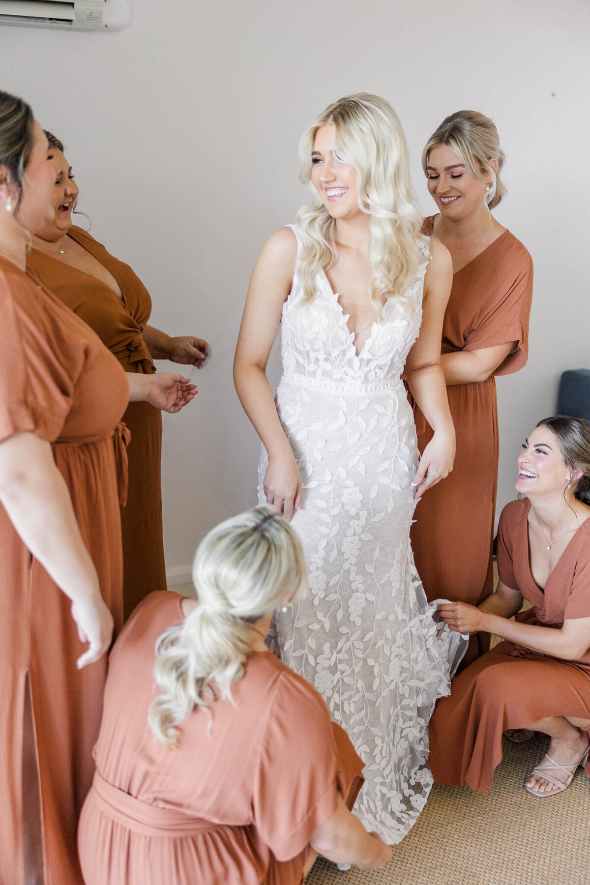 Bride, surrounded by her bridesmaids on her wedding day morning