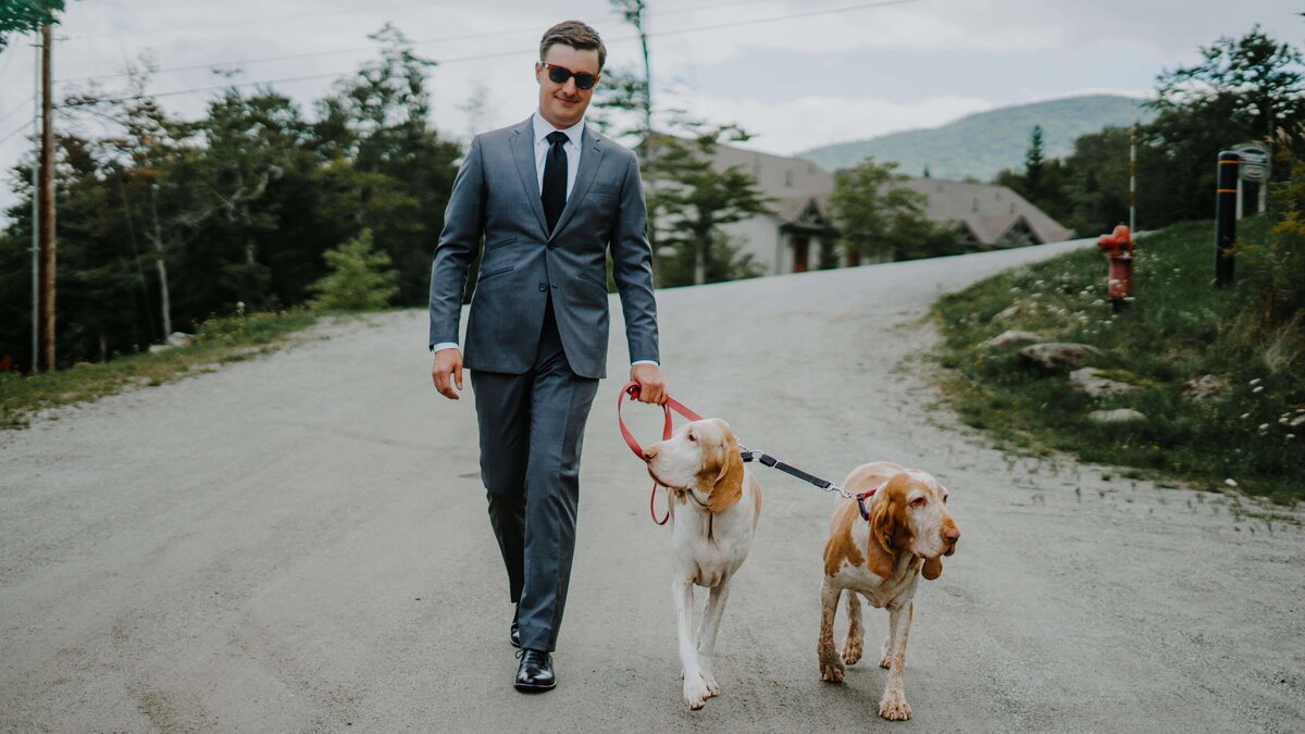 a groom with his two dogs on a leash
