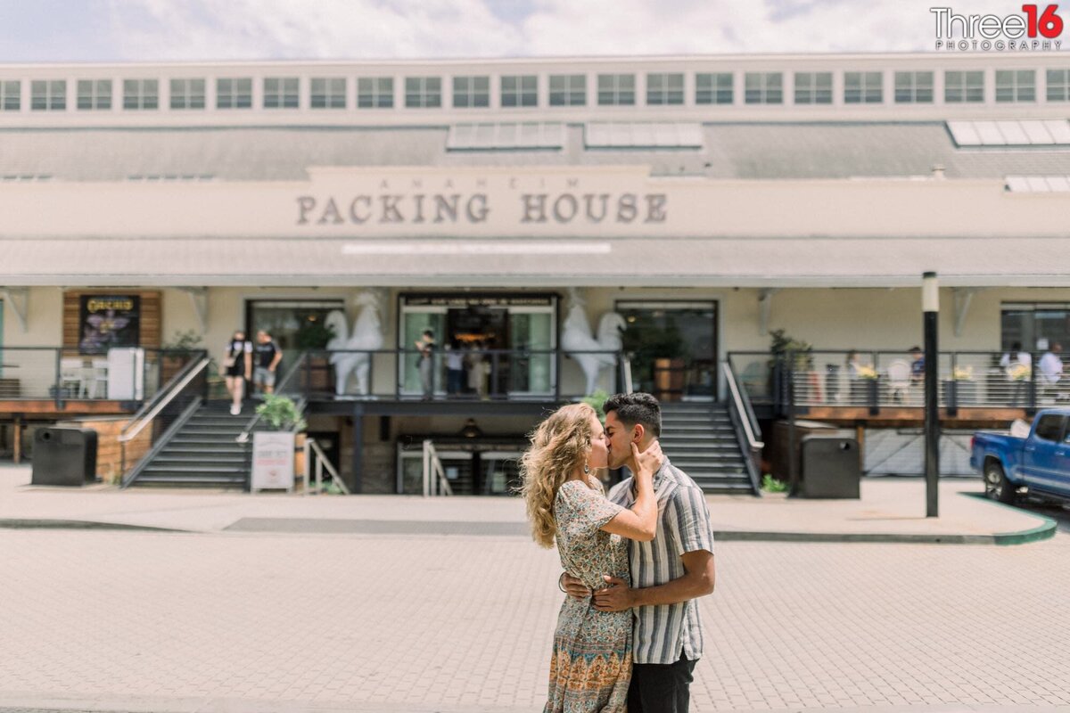 Engaged couple share a sweet kiss in front of the Packing House in Anaheim, CA