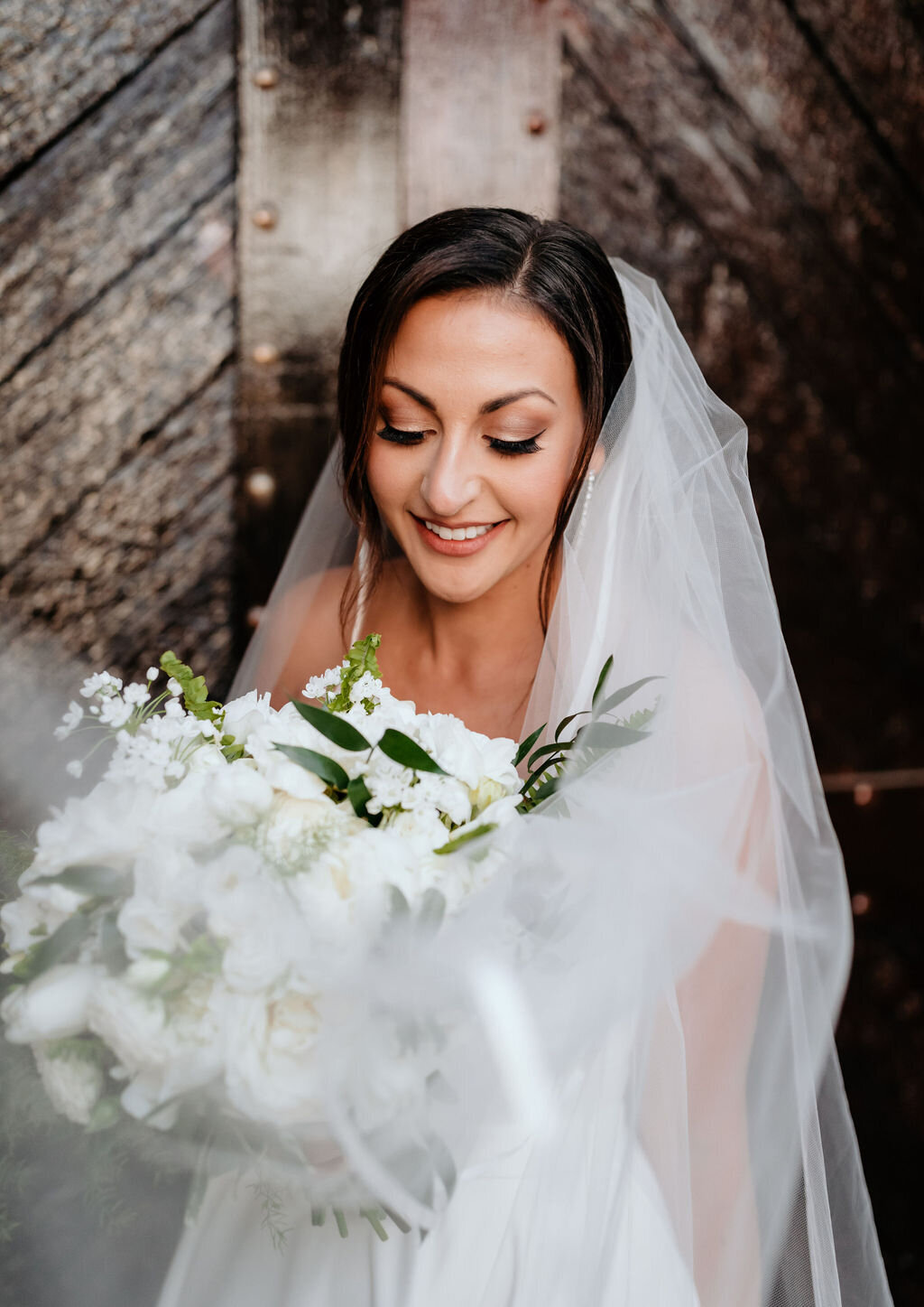 Bridal portrait at the Palm Event Center in Pleasanton, CA, captured during a spring wedding. The bride holds a white flower bouquet and her veil elegantly drapes around her.