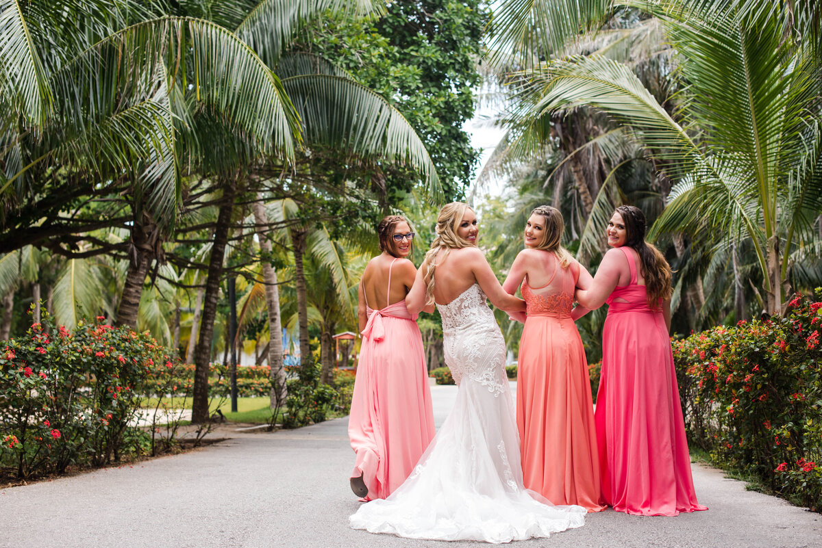a bride and bridesmaids walking by palm trees in the Riviera Maya