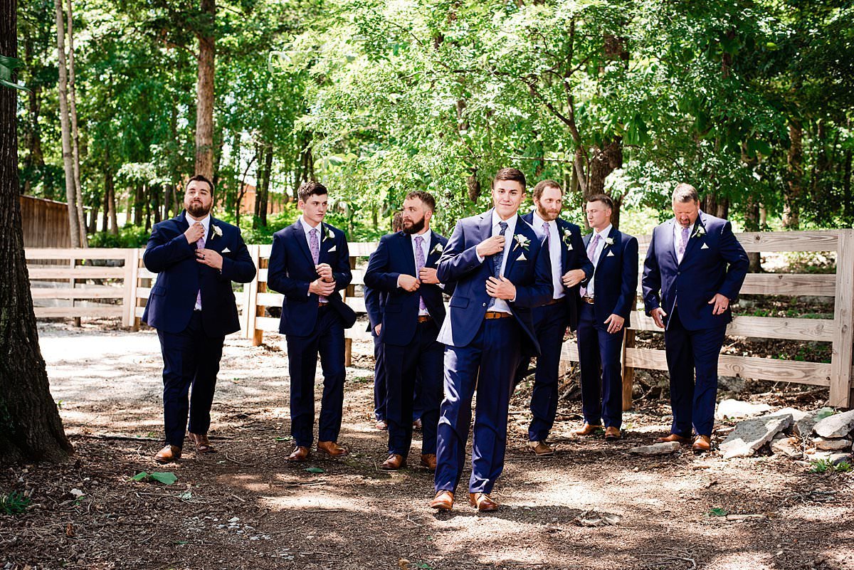 Groom with his groomsmen around him walking near a white fence