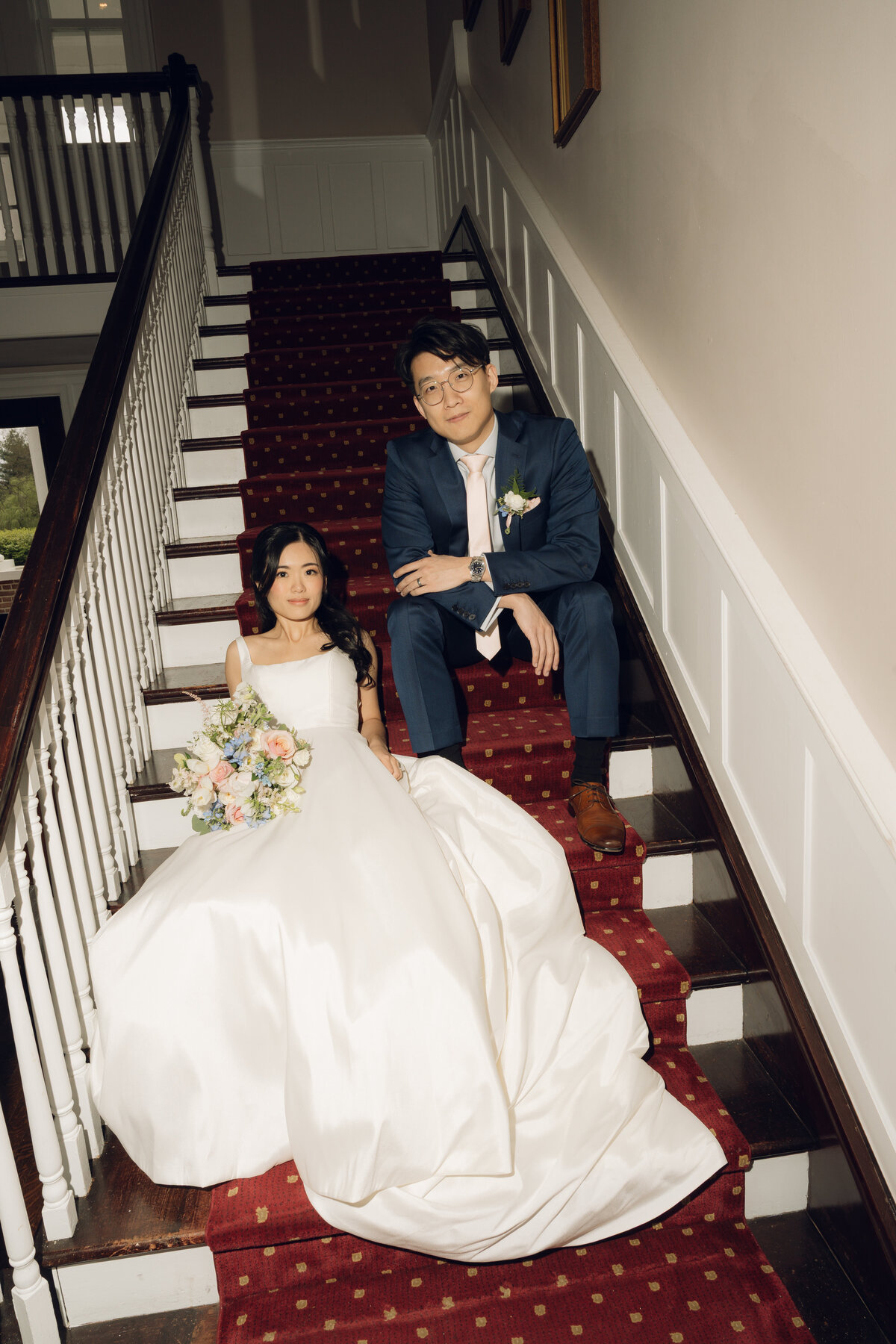 A bride and groom sitting posed on the stairs of their wedding venue in Virginia. 