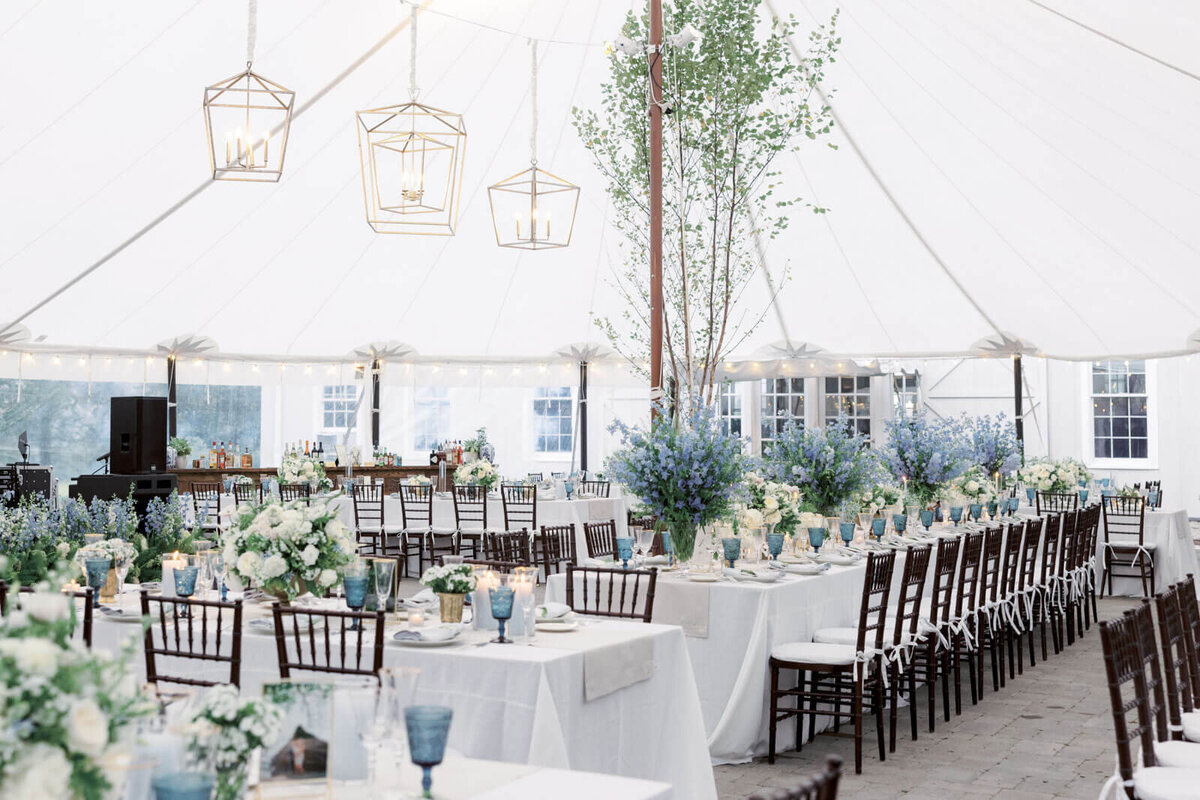 An elegant wedding tent reception venue with long tables, gorgeous flower centerpieces at The Lion Rock Farm, CT. Image by Jenny Fu Studio