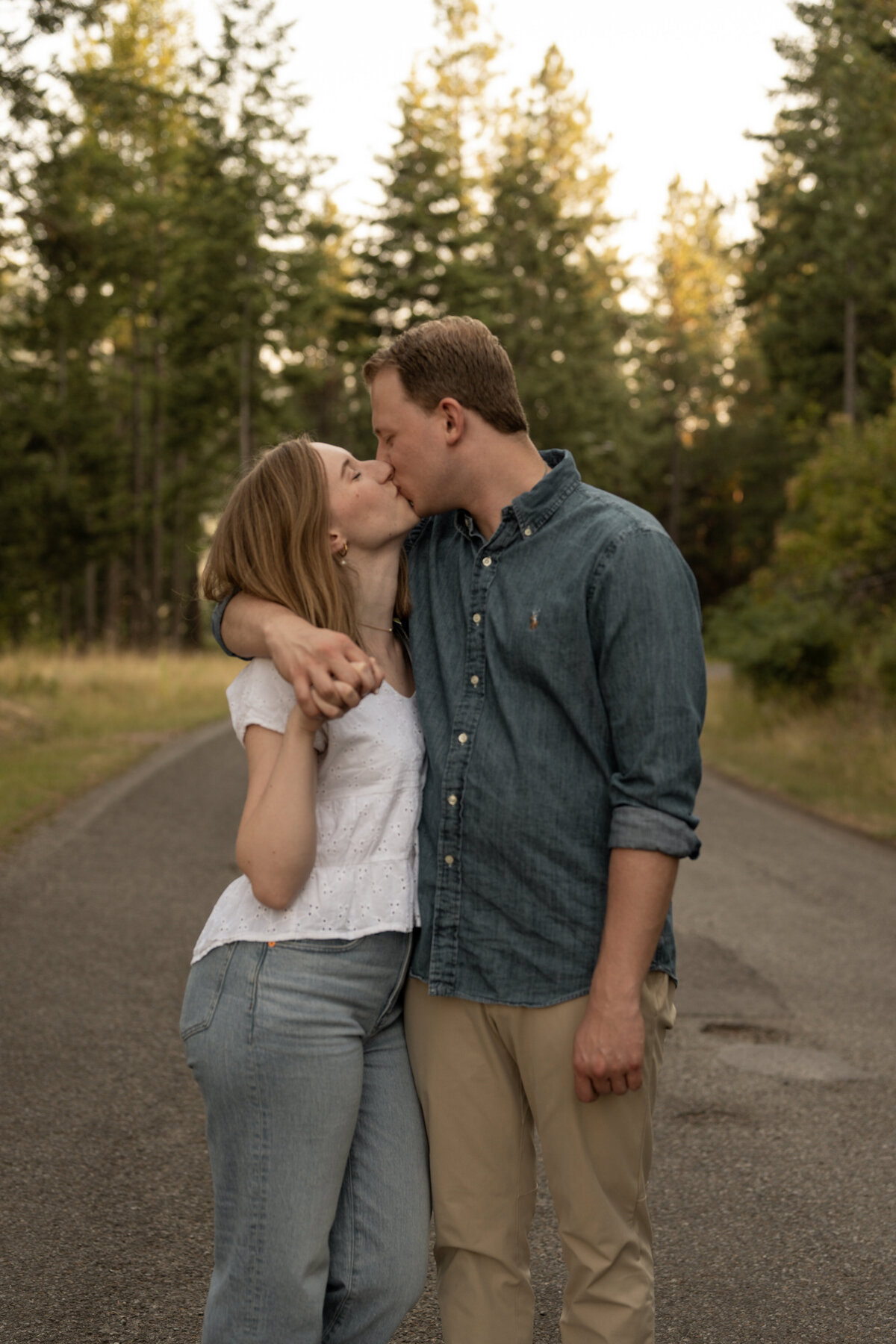 couple kissing on a path in the forest by photographers in idaho