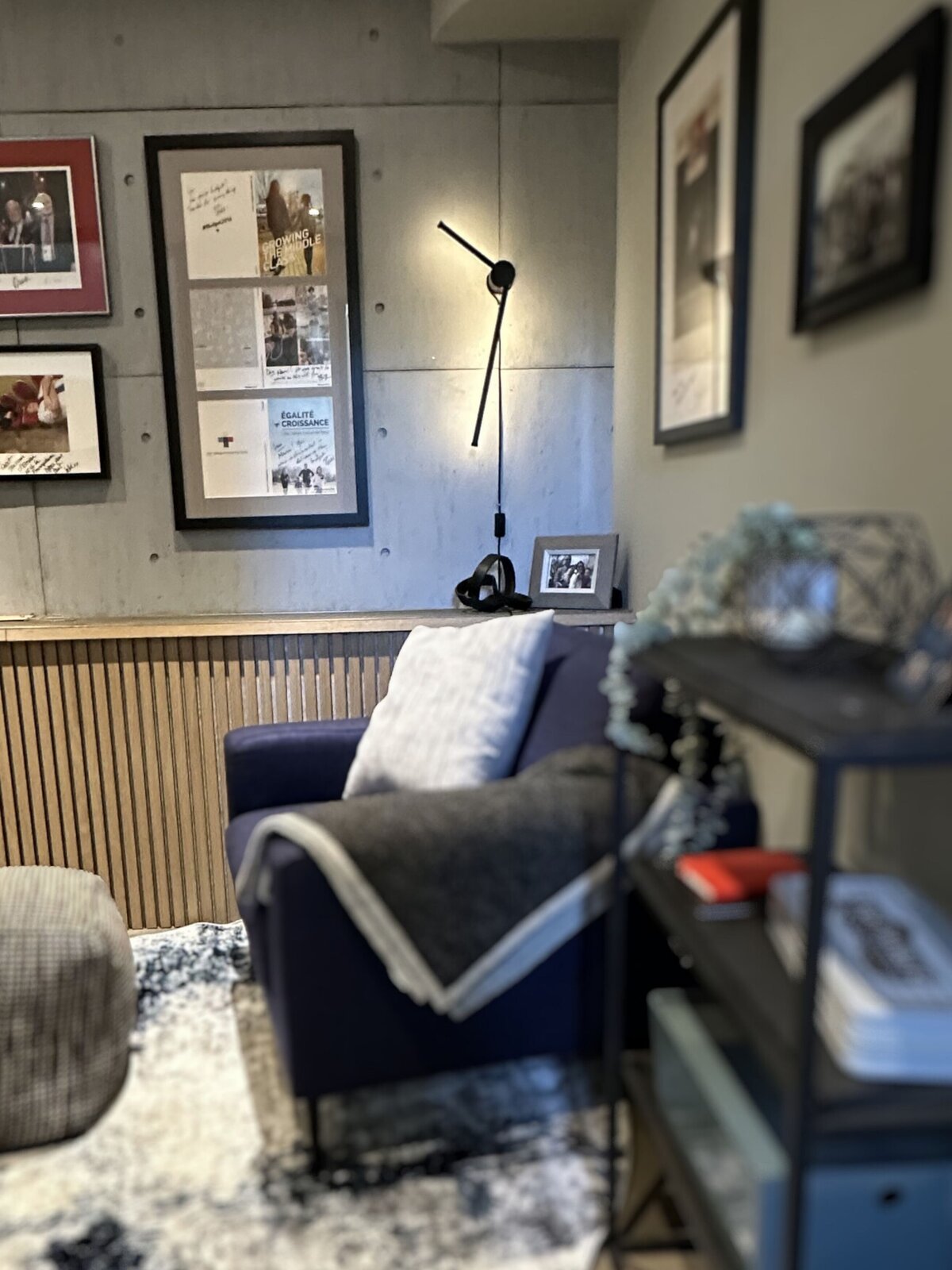 Masculine modern home office with blue armchair, striking linear wall light, and framed artwork on faux concrete wall by Urbanomic Interiors, Ottawa (Westboro).