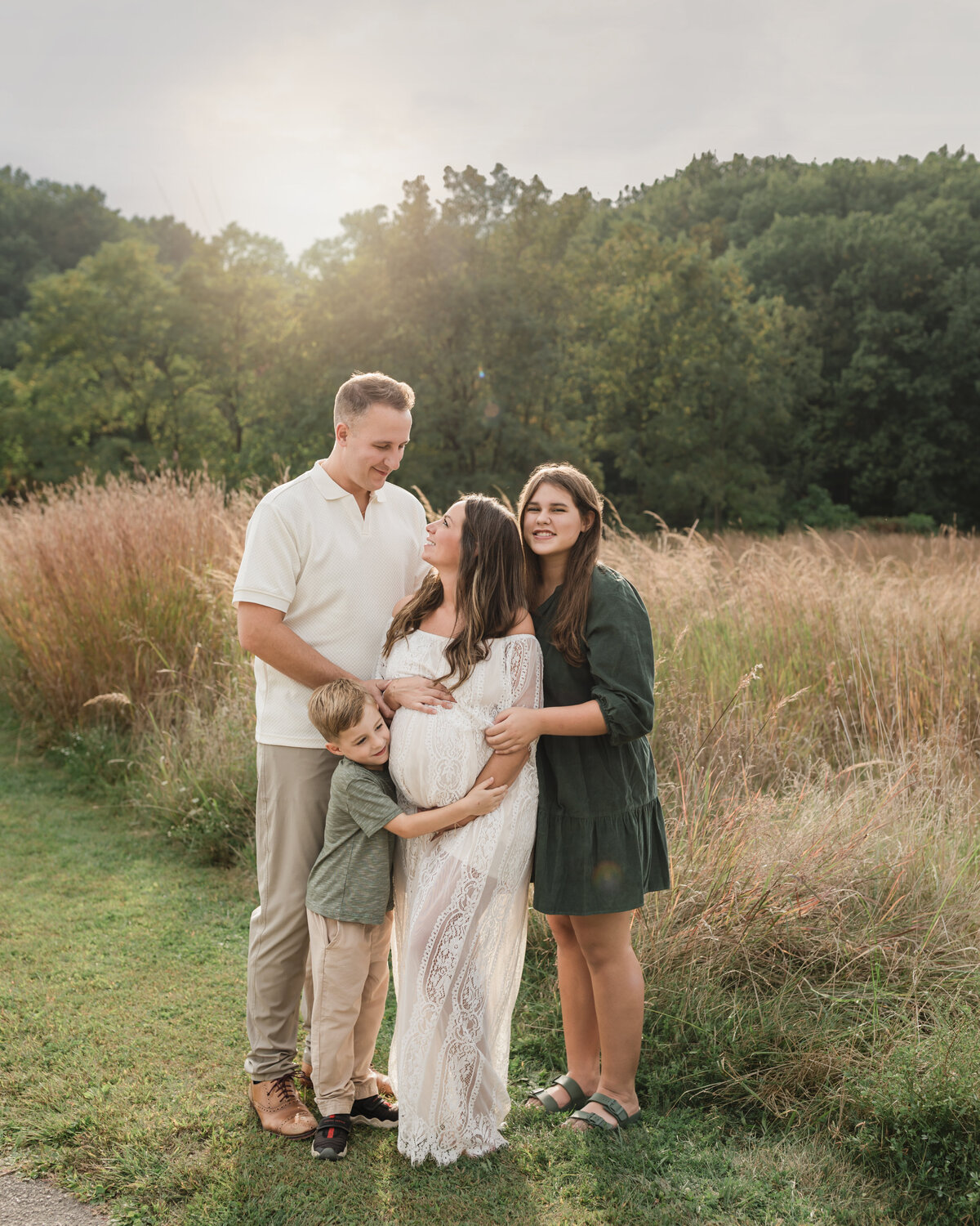 parents and two children hugging in park for family photos