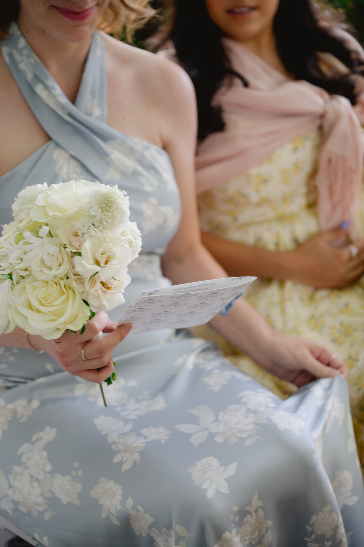 Bridesmaid holding a bouquet of white flowers with a program at the Chicago Botanic Gardens.