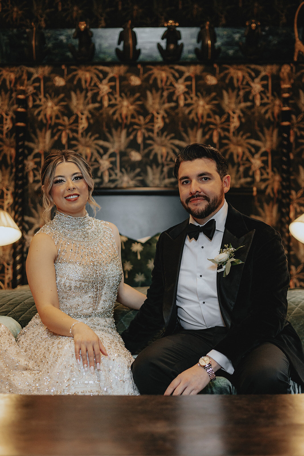 Bride and groom smiling with funky wallpaper in the back
