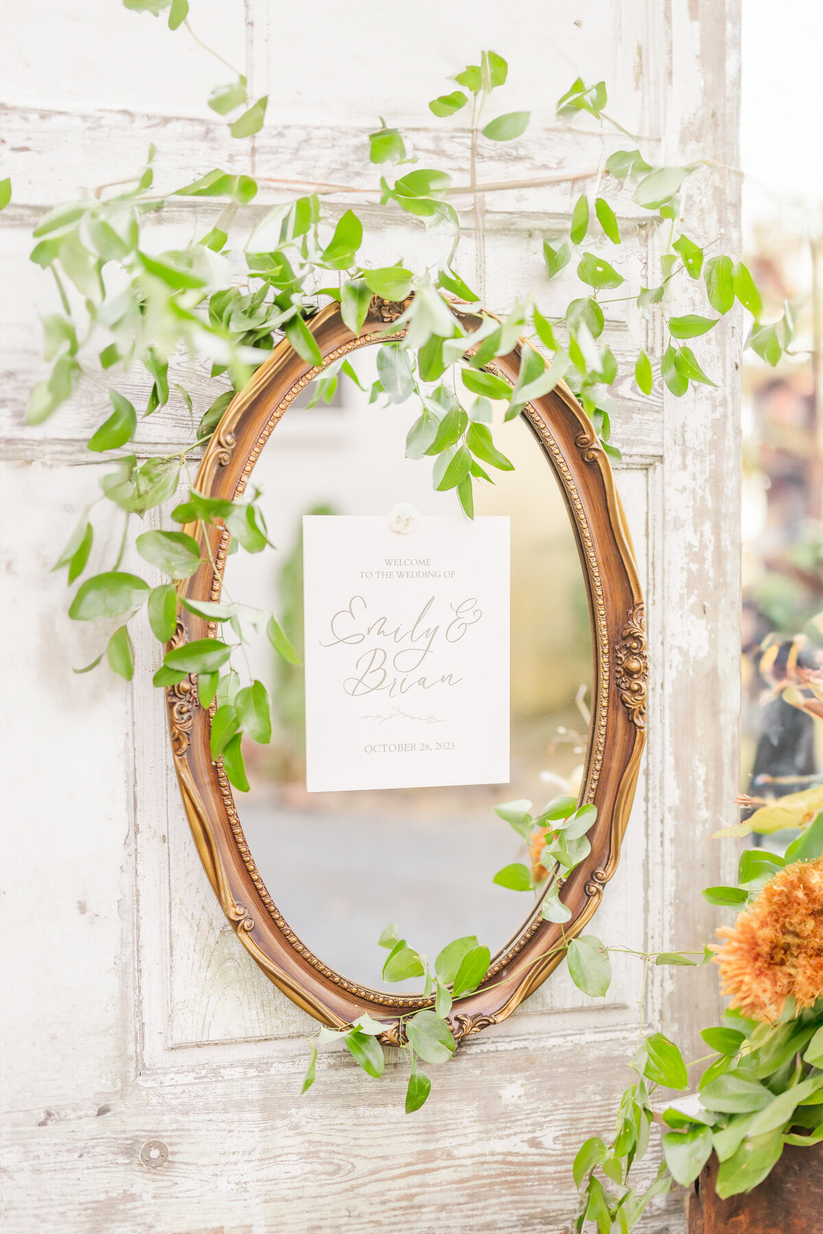 A mirror hangs on a wooden door with a wedding announcement stuck to it