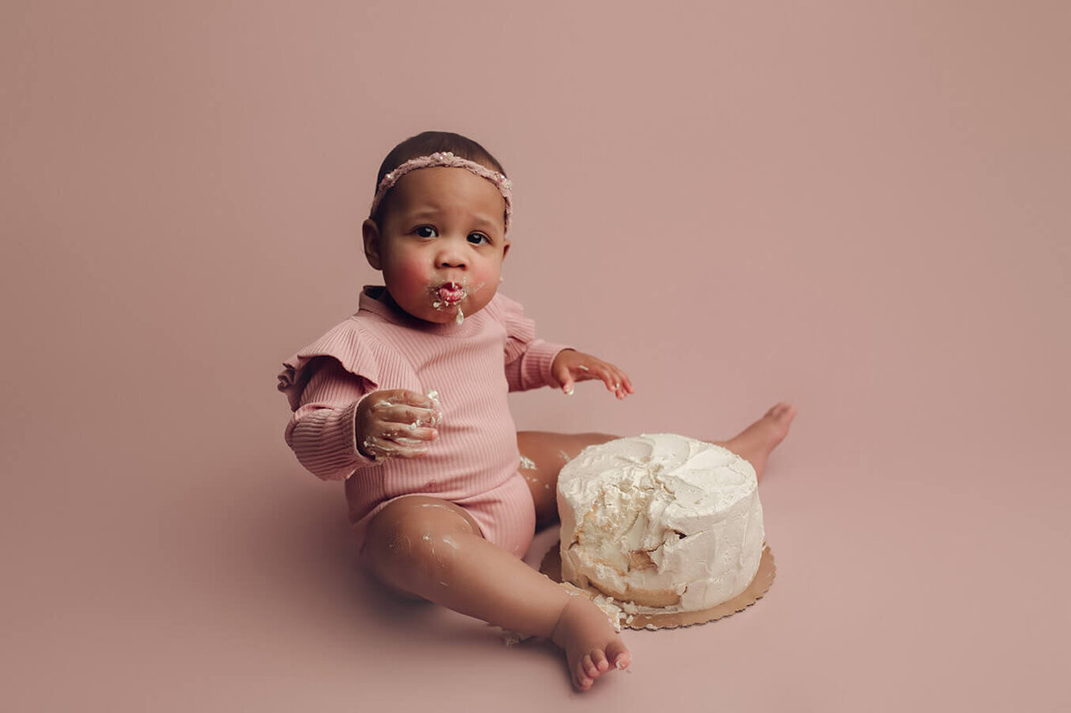 a one year old girl with a mouth full of cake in rochester ny