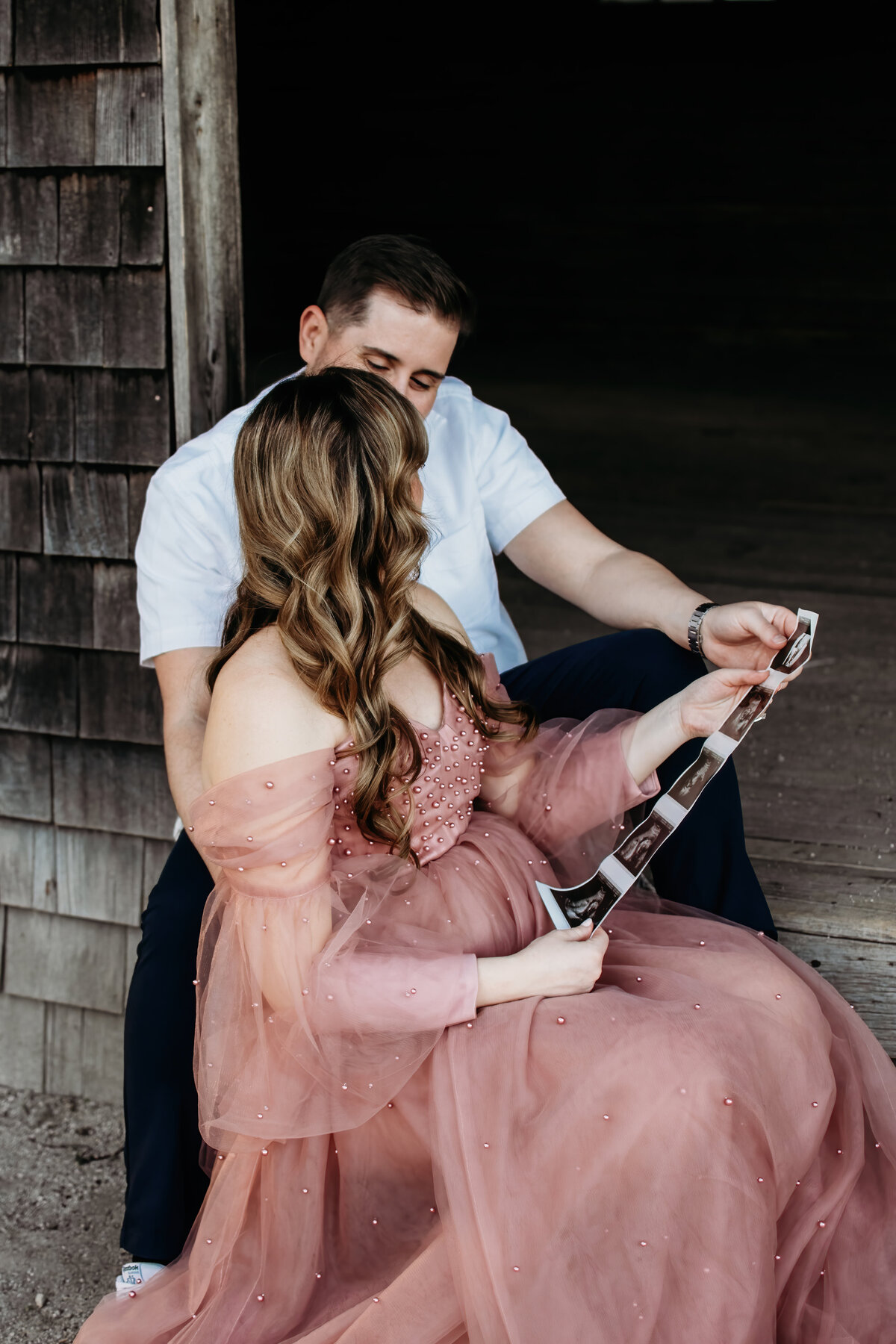 Mom and dad looking at baby girl on the ultrasound while embracing each other  during a maternity photoshoot in Batavia, IL