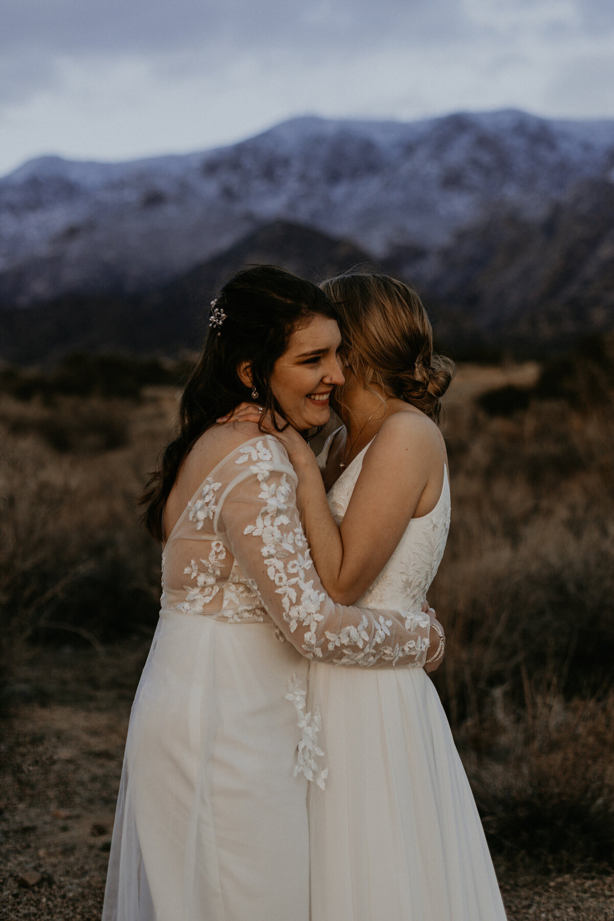 newlywed brides holding each other in front of the Sandia mountains in Albuquerque, New Mexico