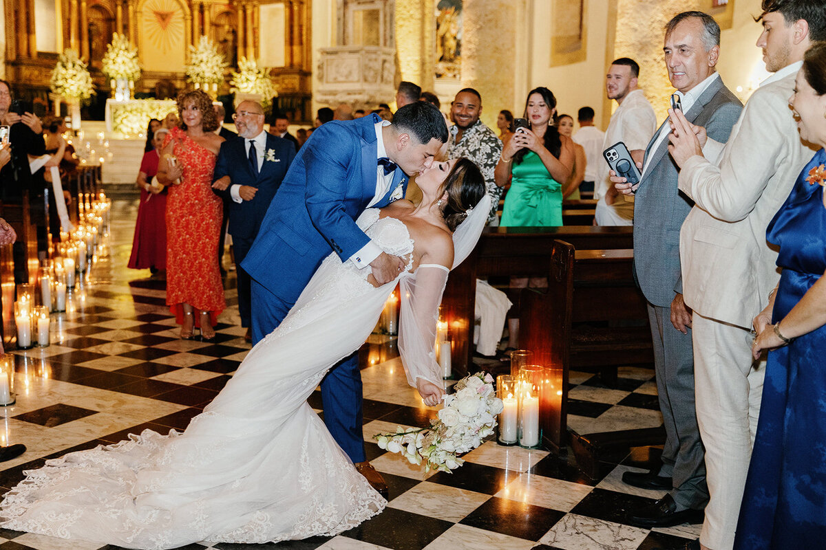 A dramatic dip kiss at the altar as guests cheer, celebrating Victoria and Daniel’s Cartagena destination wedding.