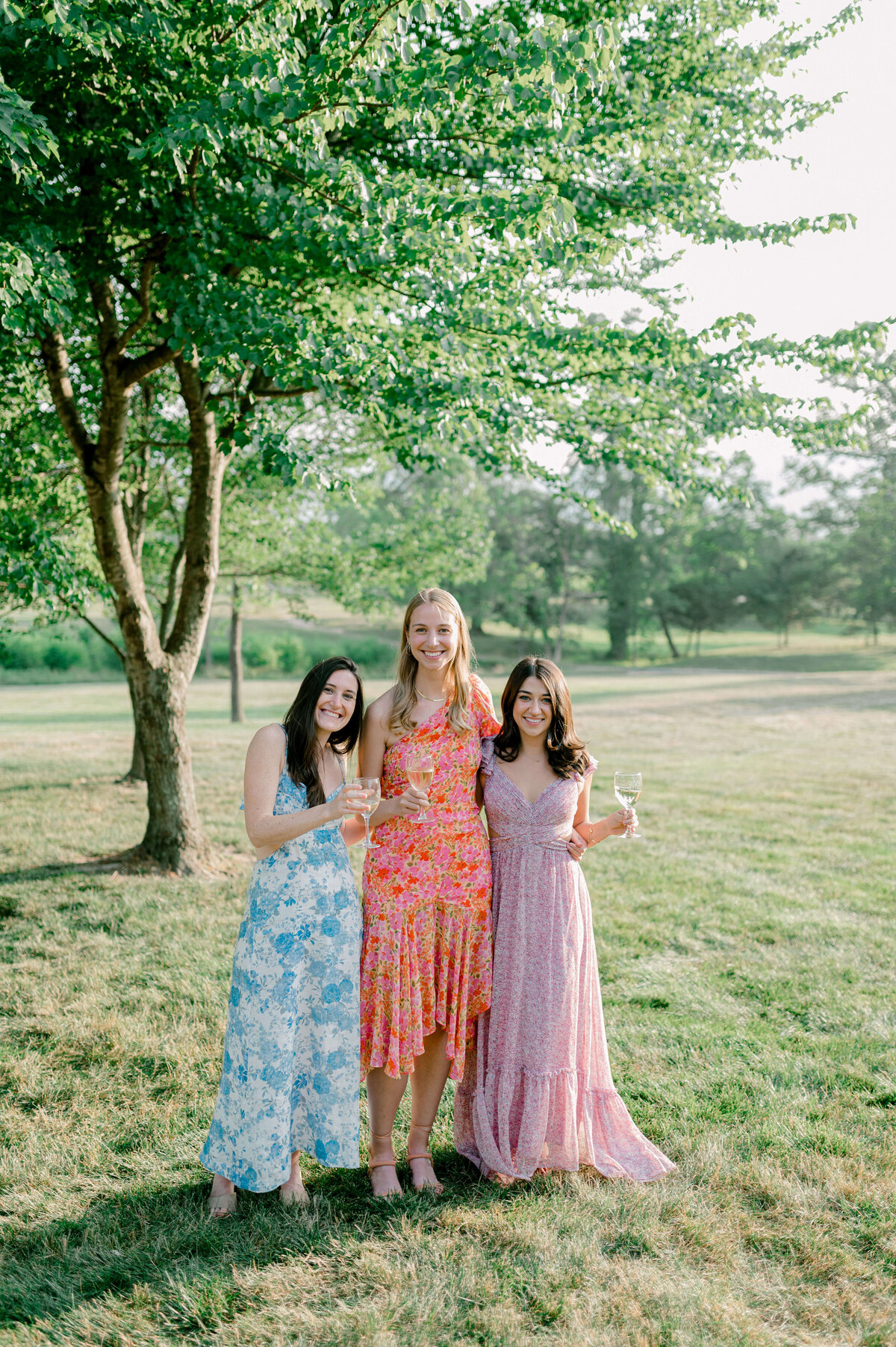 Guests in floral dresses  coming together to take a photo during an outdoor cocktail hour