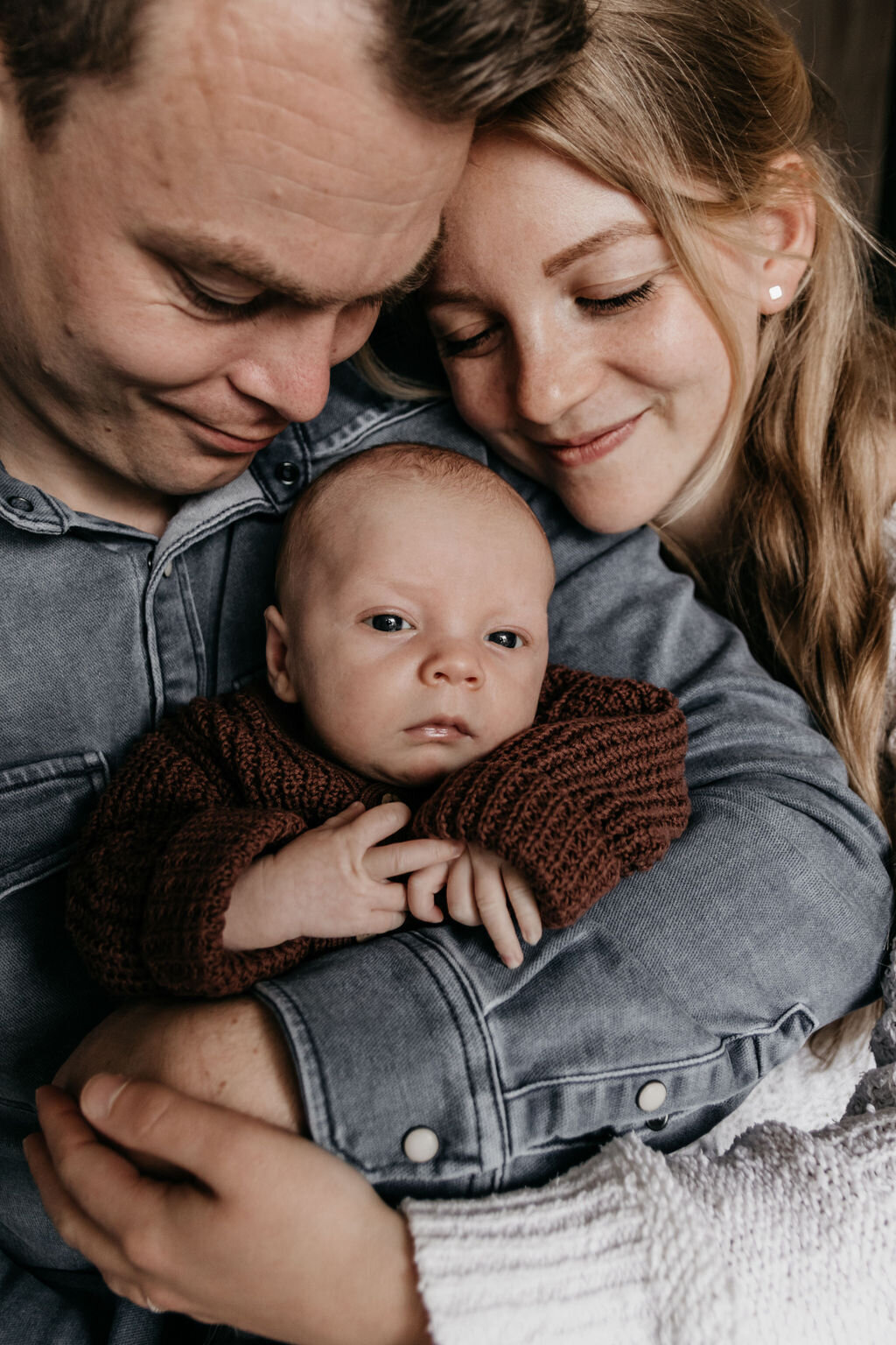 Ouders knuffelen met newborn baby tijdens een newbornshoot in Noord-Nederland