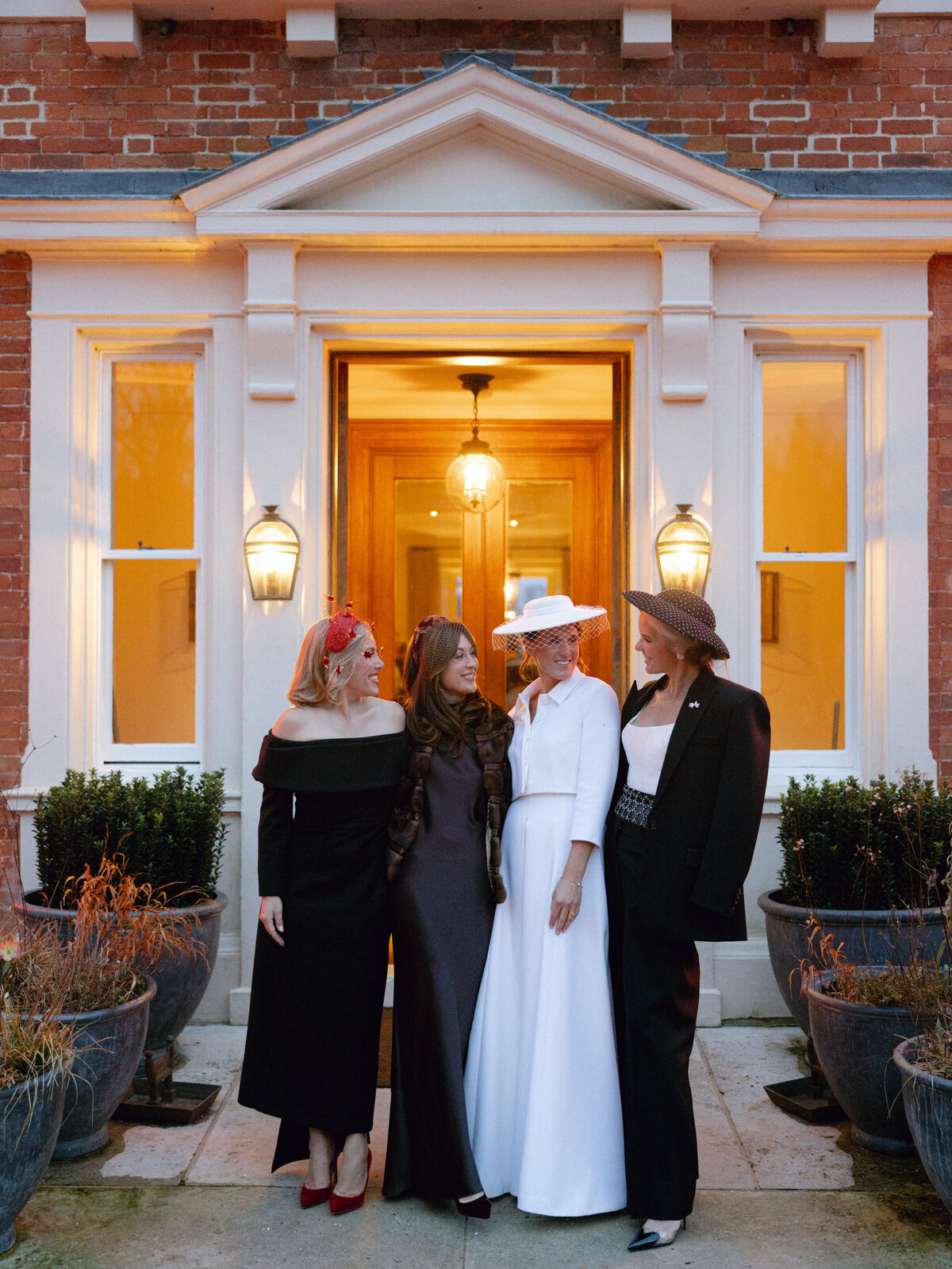 Bride wearing hat standing next to friends at wedding