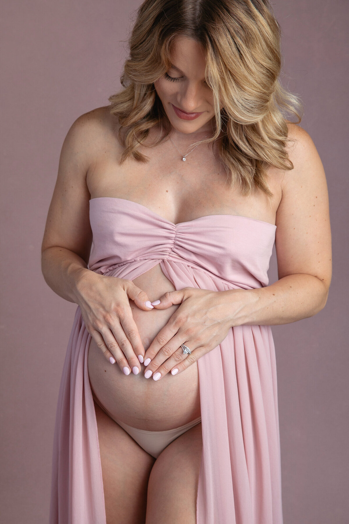 closeup photo of a pregnant woman looking down at her baby belly.