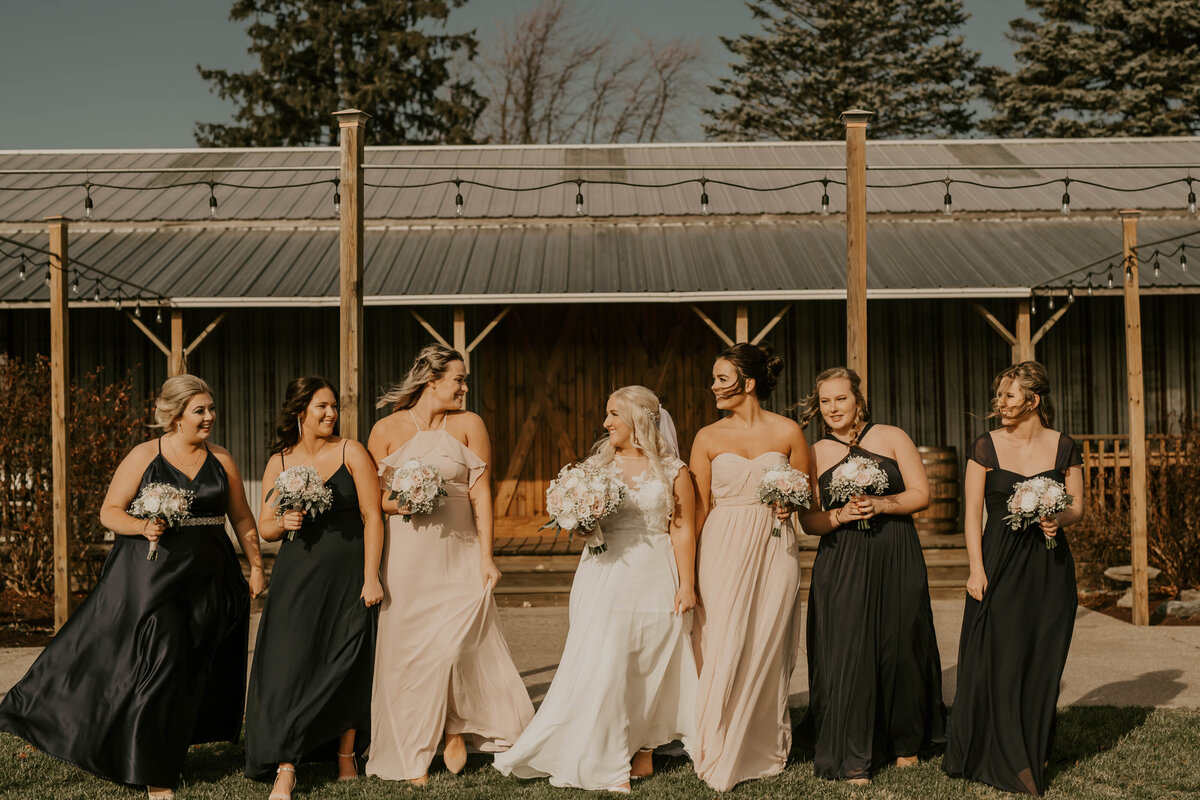 bride and her bridesmaids walk together smiling at each other for photos.
