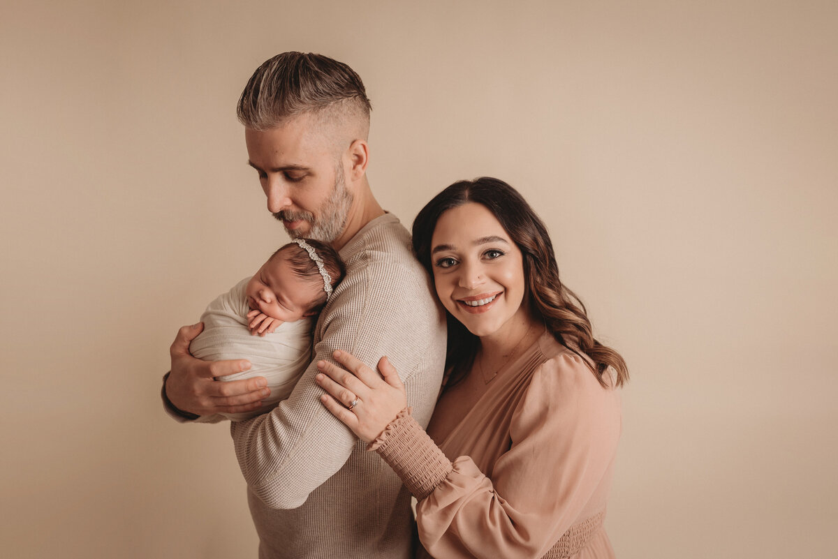 Beautiful newborn family portrait on tan backdrop at newborn photography studio in Marietta, GA, Casey McMinn Photography