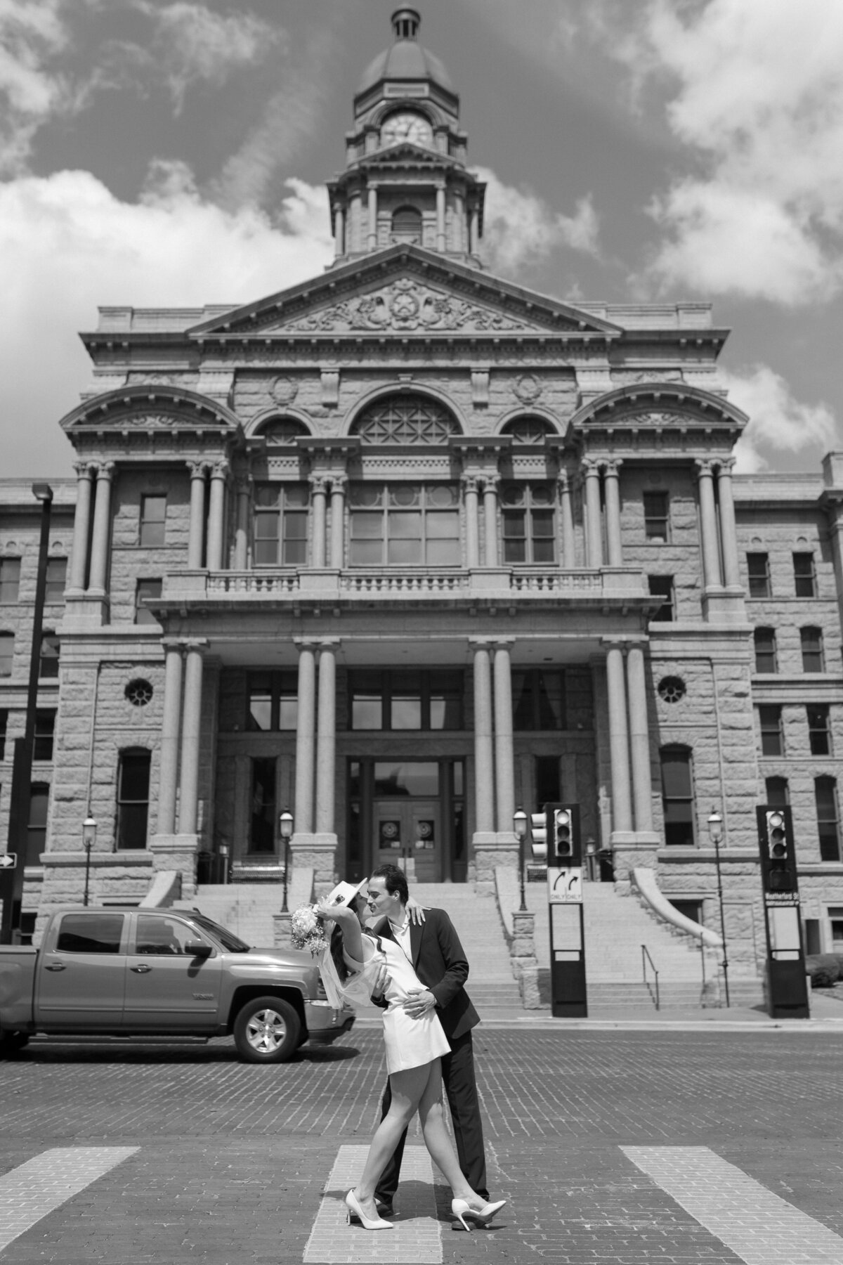 Couple embracing outside Fort Worth courthouse during wedding portraits.