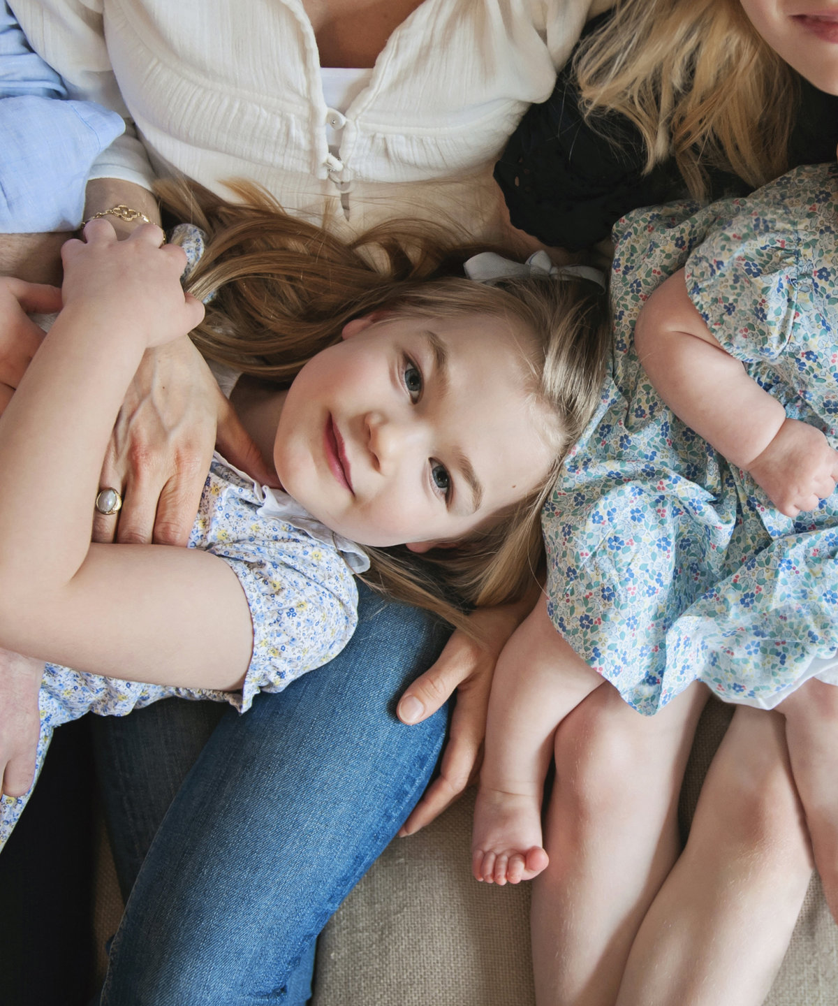 A little girl cuddled by her family during a family photo shoot in Weybridge