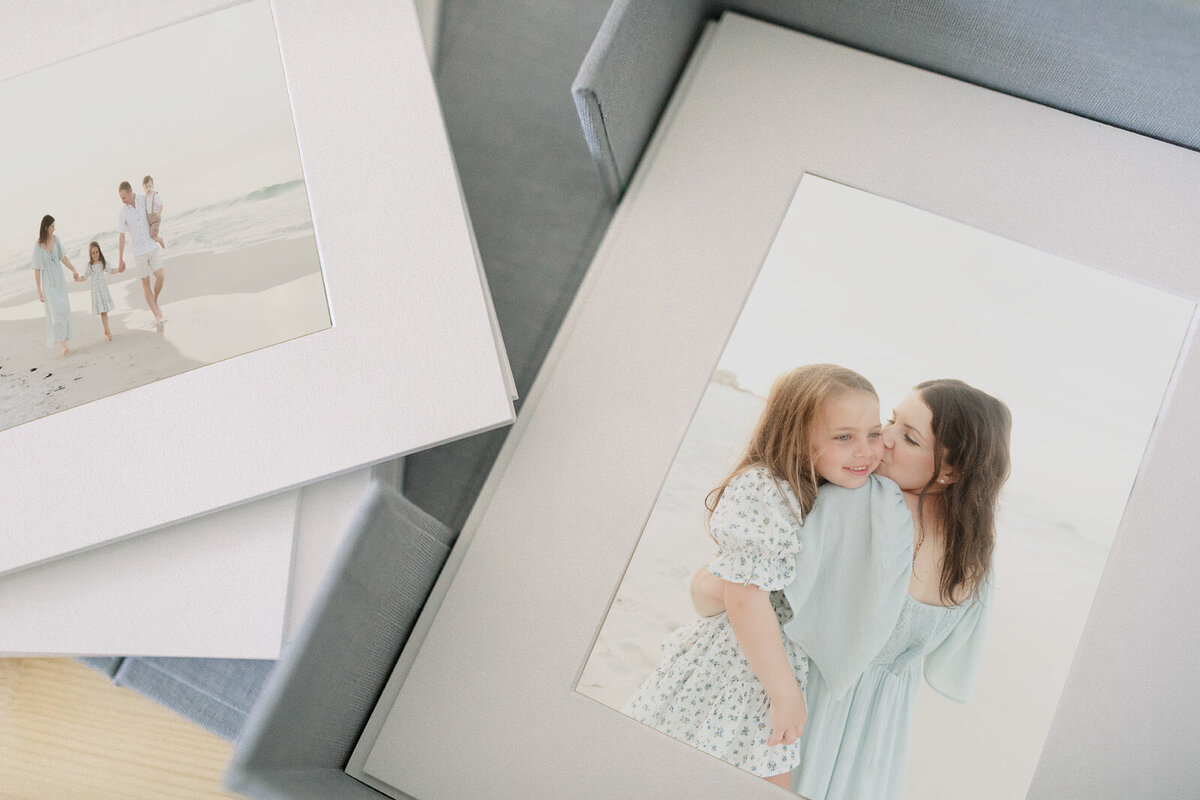 Custom matted prints featuring family portraits on the beach, displayed in a linen photo box