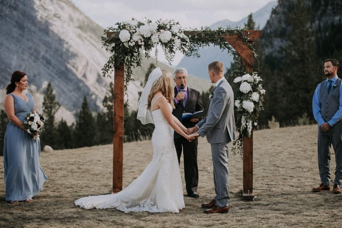 Wooden ceremony arch with elegant florals by Hen & Chicks, classic Calgary, Alberta wedding florist, featured on the Brontë Bride Vendor Guide.