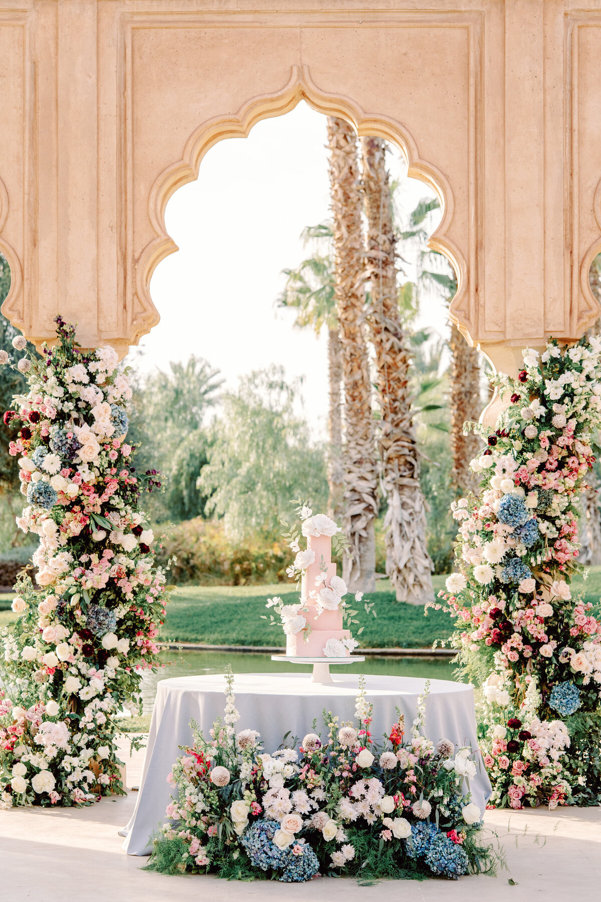 Wedding cake table surrounded by floral installations at Palais Namaskar Morocco for a destination wedding photographed by Italy photographer