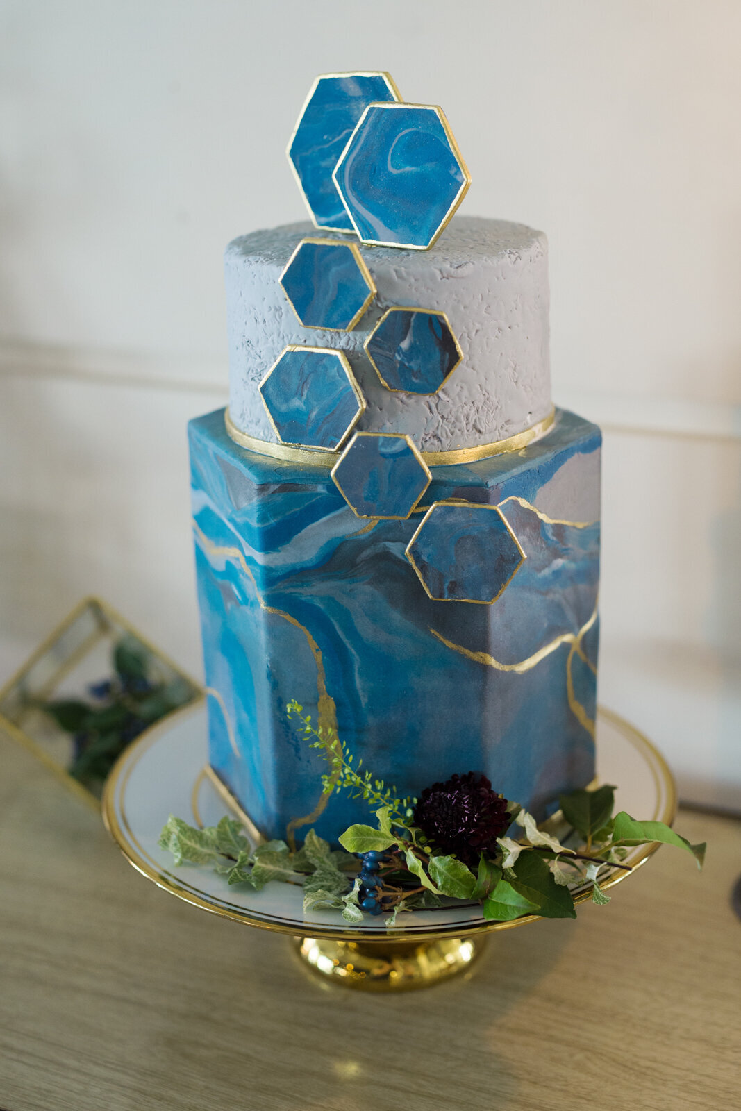 Trendy, two-tiered, blue and gold marbled wedding cake with geometric shapes created by Bake My Day, contemporary cakes & desserts in Calgary, Alberta, featured on the Brontë Bride Vendor Guide.