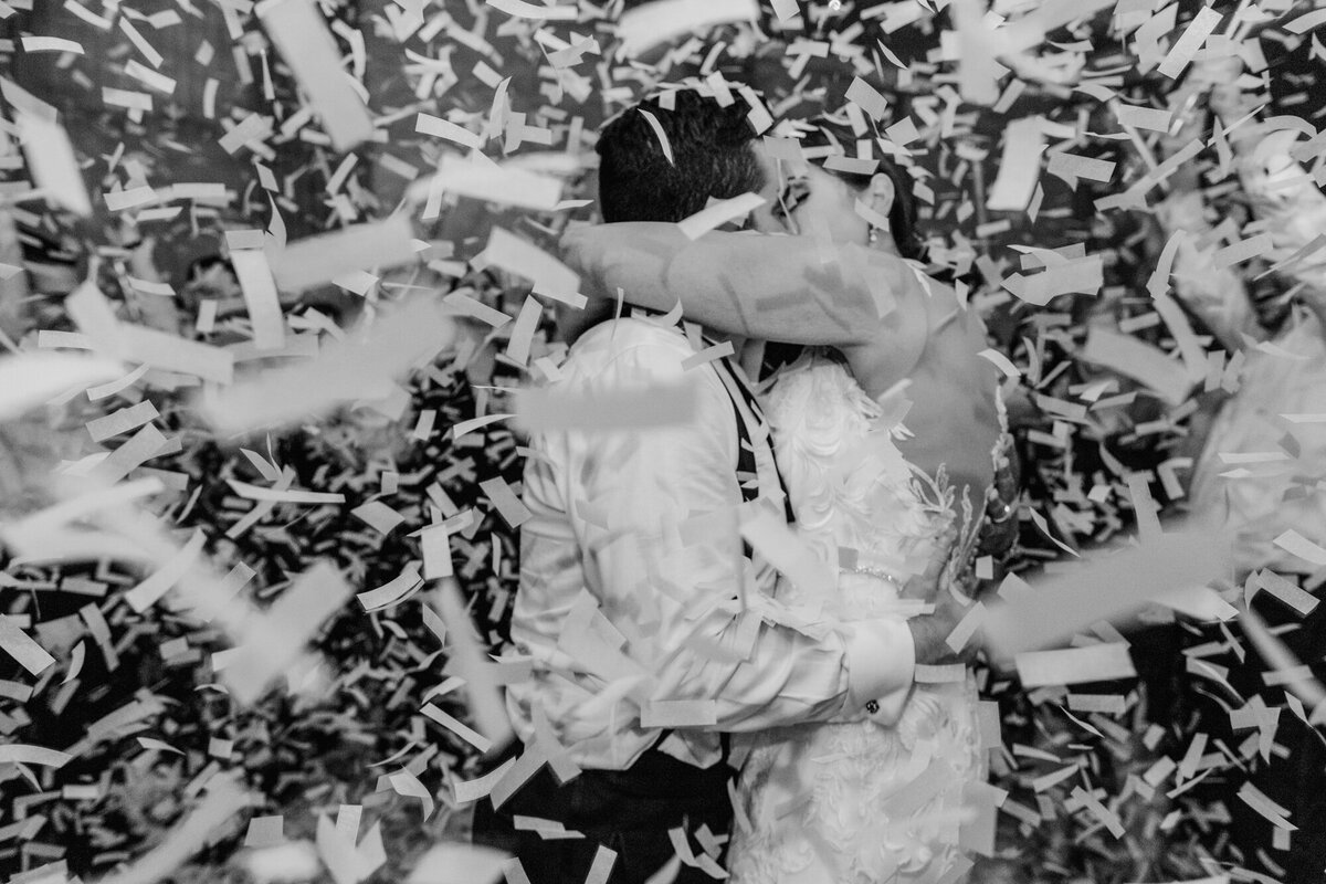 Confetti falls at the end of a wedding reception as the newlyweds share a kiss