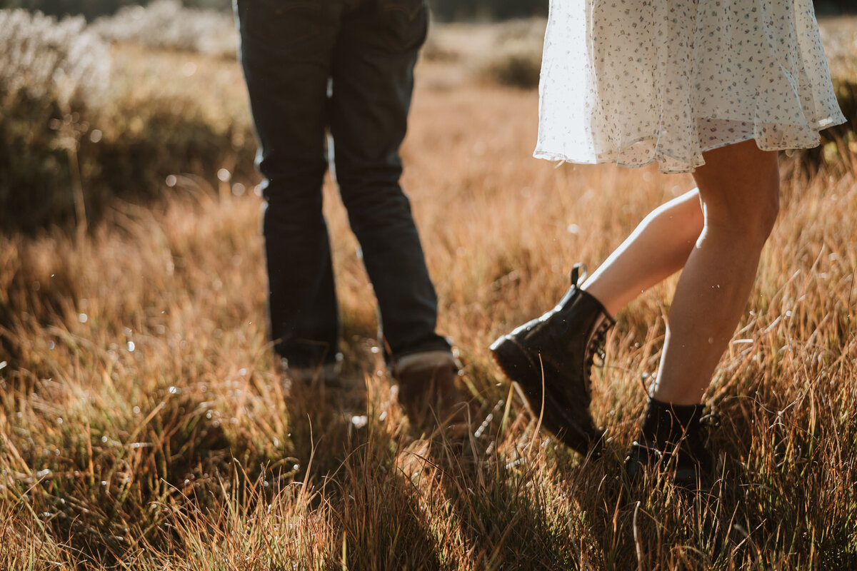 Close-up of a couple walking through golden grass, capturing rustic engagement vibes in Breckenridge, Colorado.
