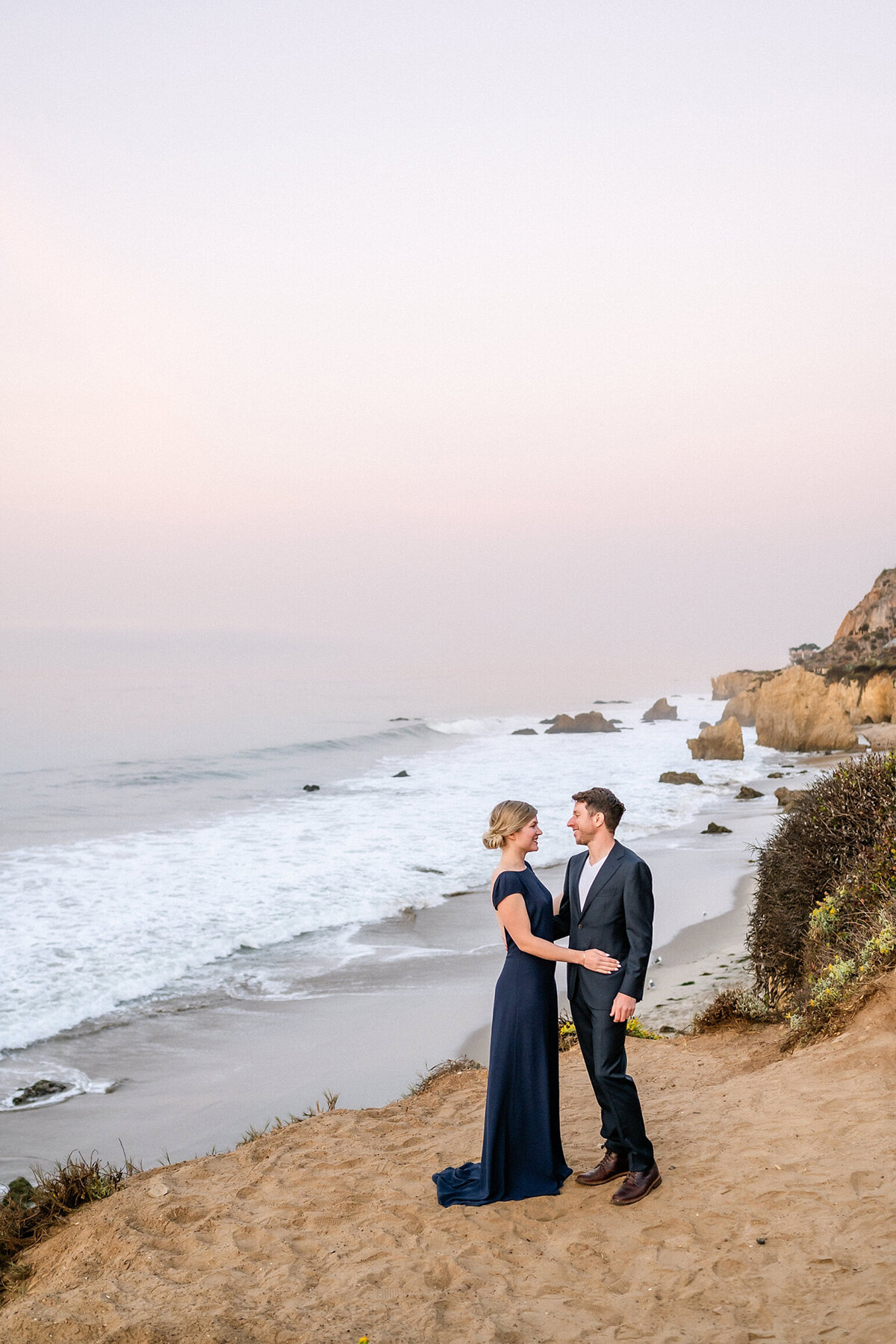 Engaged Couple standing on a cliff over looking the ocean