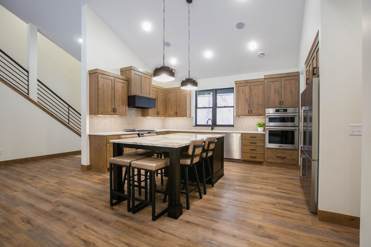 Open kitchen with dark cabinets, large island, and quartz countertops in an Elk River custom home