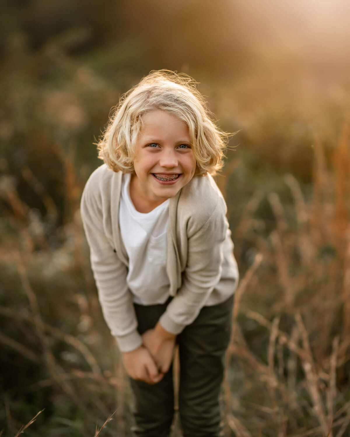 A tween boy poses cutely and smiles big for the camera during his portrait session with an Asheville Family Photographer