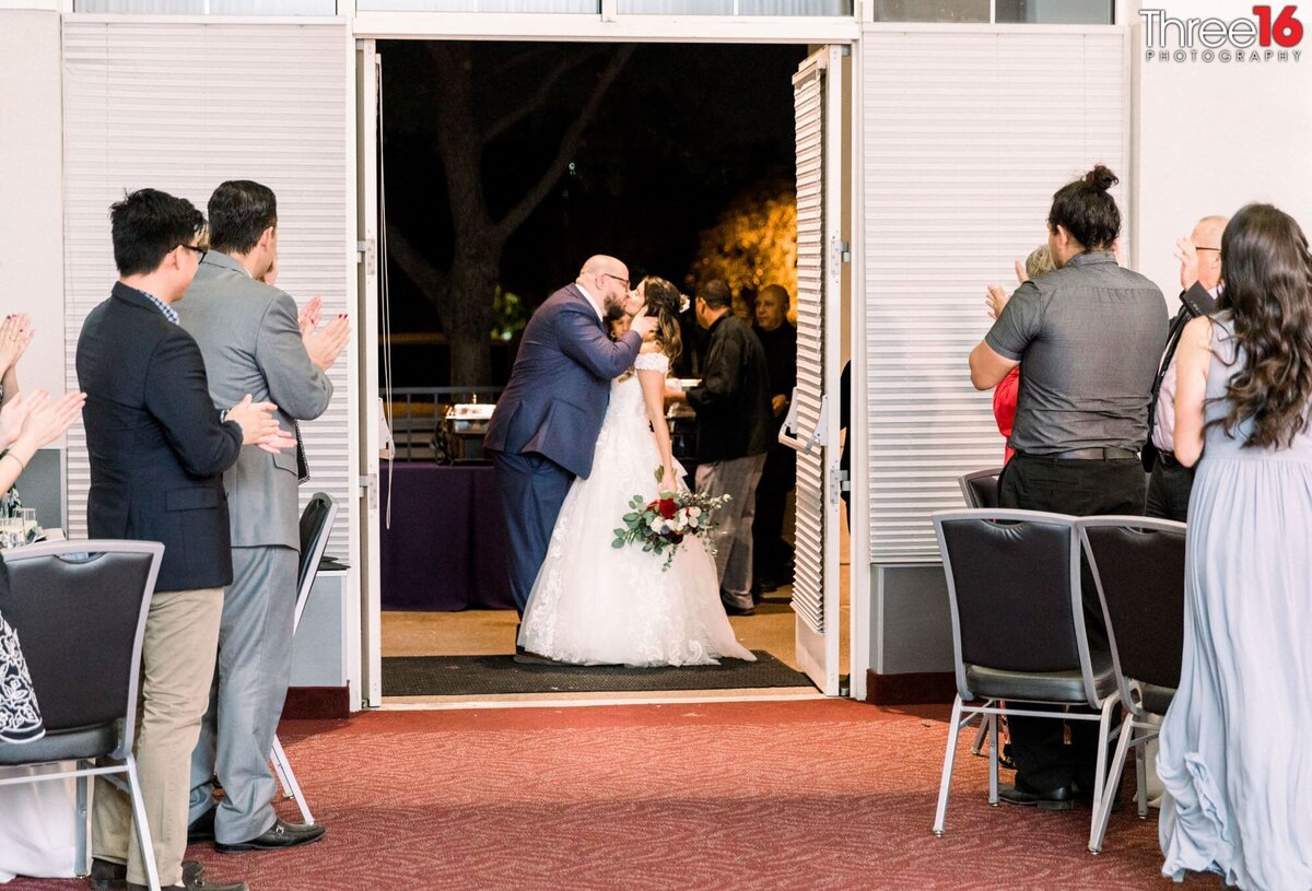 Bride and Groom are seen kissing as the doors to the reception open for their grand entrance
