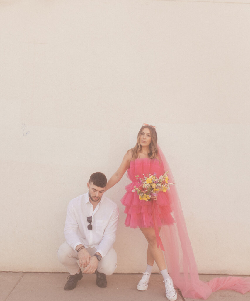 Fun and trendy couple, the bride wearing a fushia tulle short gown and pink cathedral-length veil.