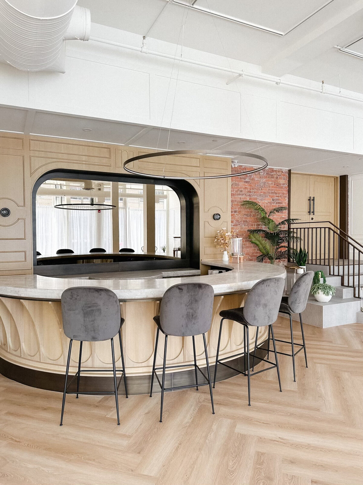 A spacious, modern event venue at Studios at Vic Park in downtown Calgary, featuring large windows with sheer white curtains, herringbone wood flooring, and contemporary furnishings. Bright natural light enhances the elegant and versatile space.