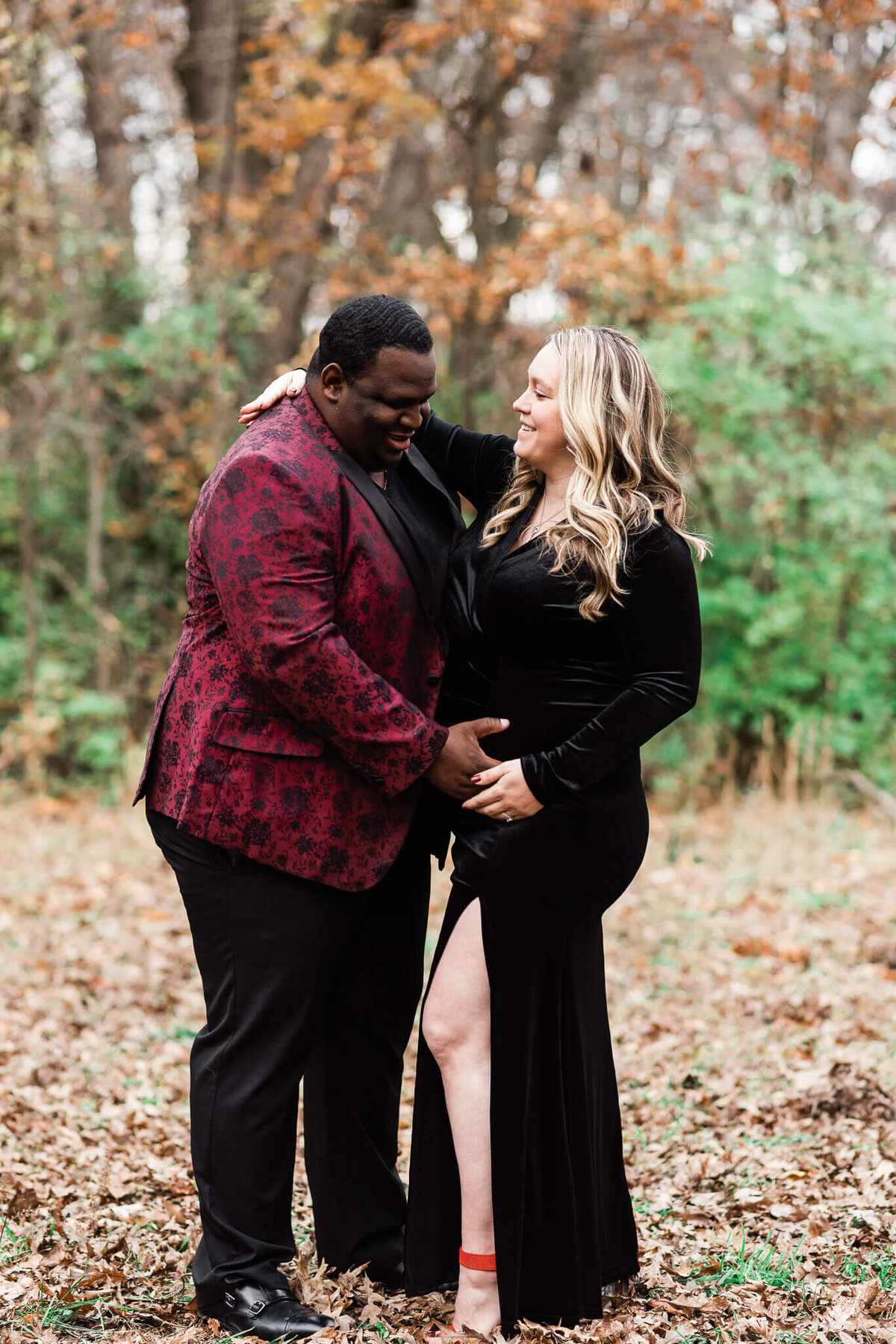 A man smiling at his wife's belly, standing in an open field in Northern Virginia