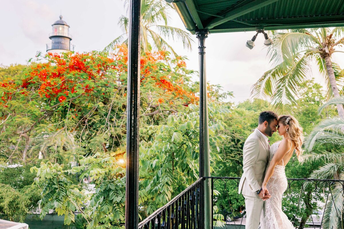 A bride and groom pose on the balcony at The Hemingway Home in Key West, Florida