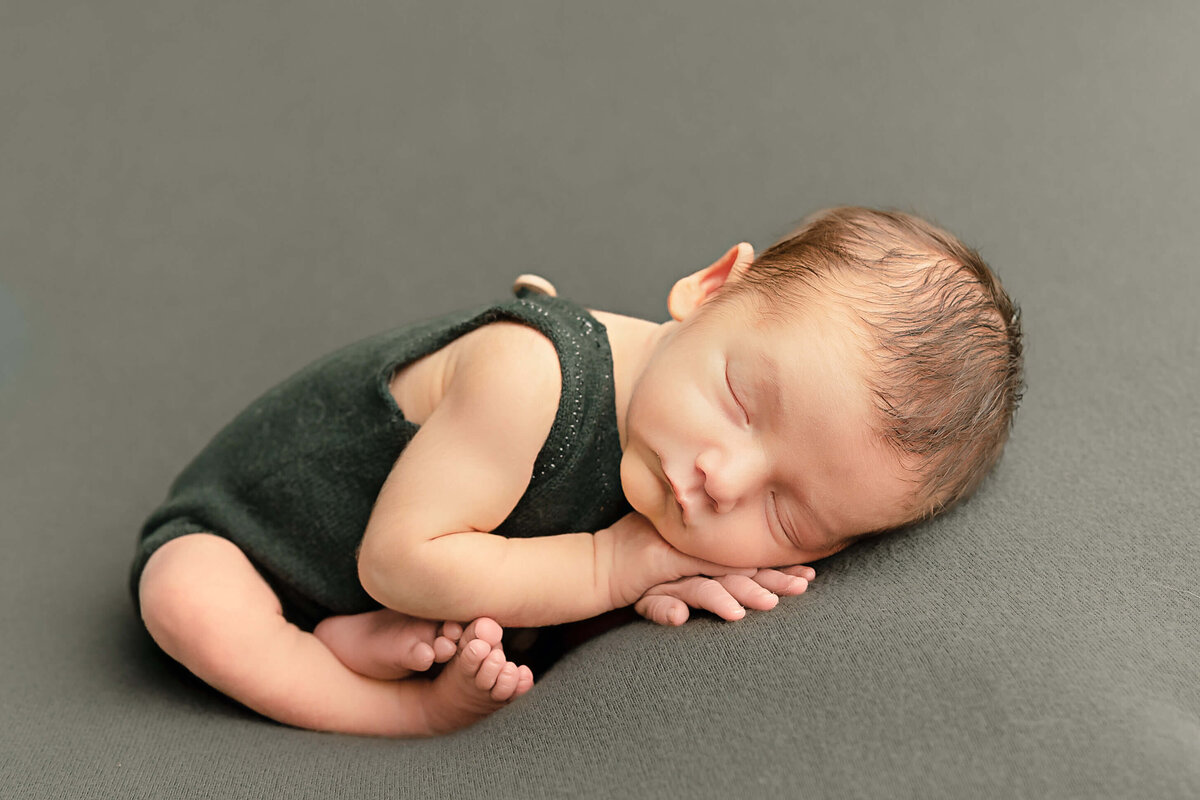 baby boy sleeping in green romper for baby photos
