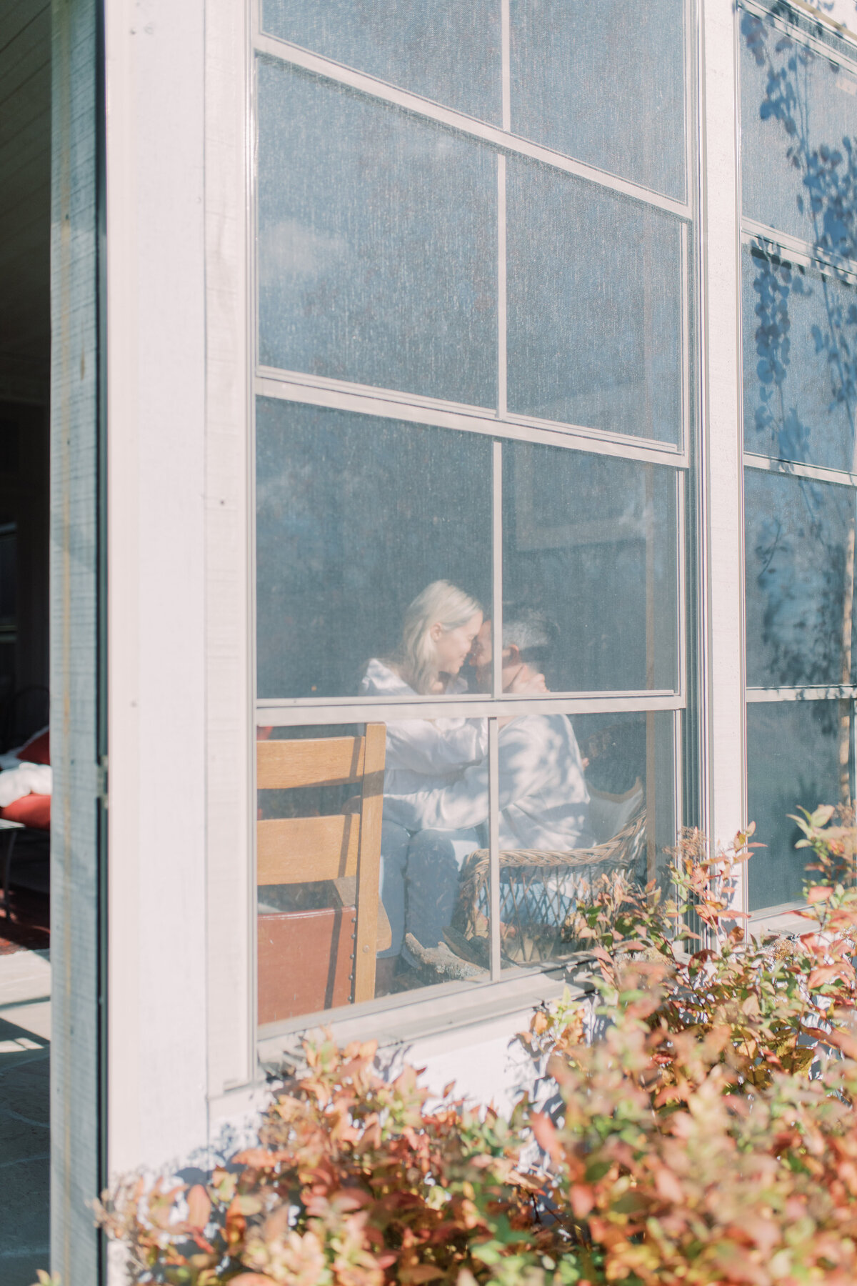 A tender kiss shared in the warm glow of a sunlit room at Elora ON with golden light filtering through the window.
